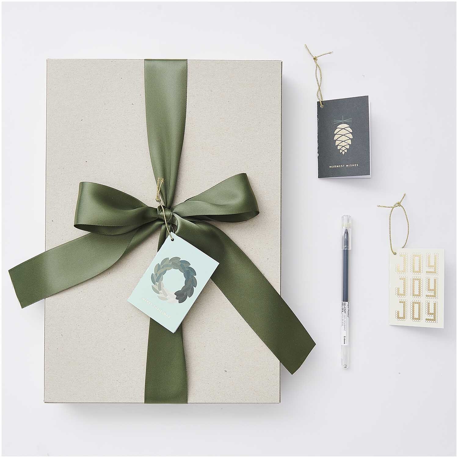 Paper Poetry Kärtchenanhänger Christmas grün 6 Stück neben Geschenkbox mit grünem Band.
