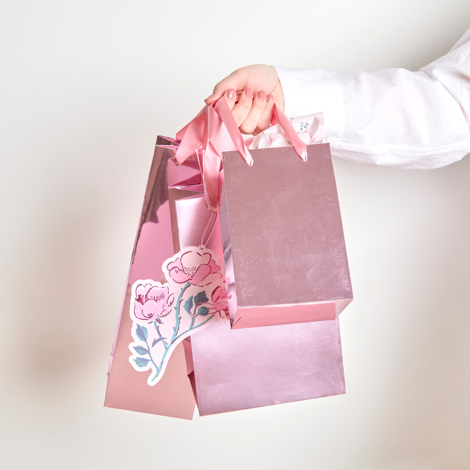 Geschenktüte Metallic Matt M 18x26x12 cm Farbe Rosa von Rico Design Flaschentüte Metallic Glänzend in Rosa, gehalten von einer Hand. Ideal für Geschenke.