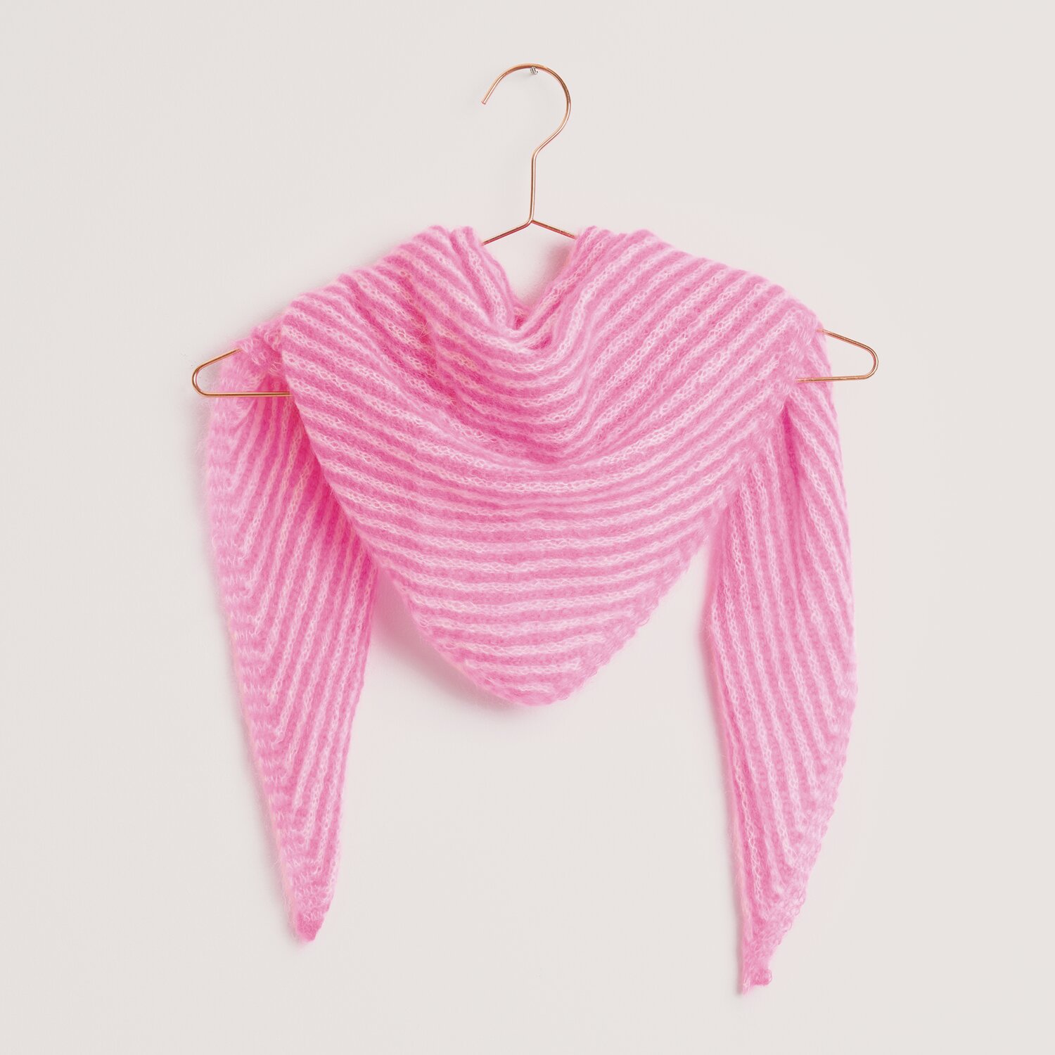 Strickset Dreieckstuch Modell 33 aus Made by Me Nr. 18, gestrickt in Weiß und Neon-Pink, hängt auf einem Kleiderbügel.