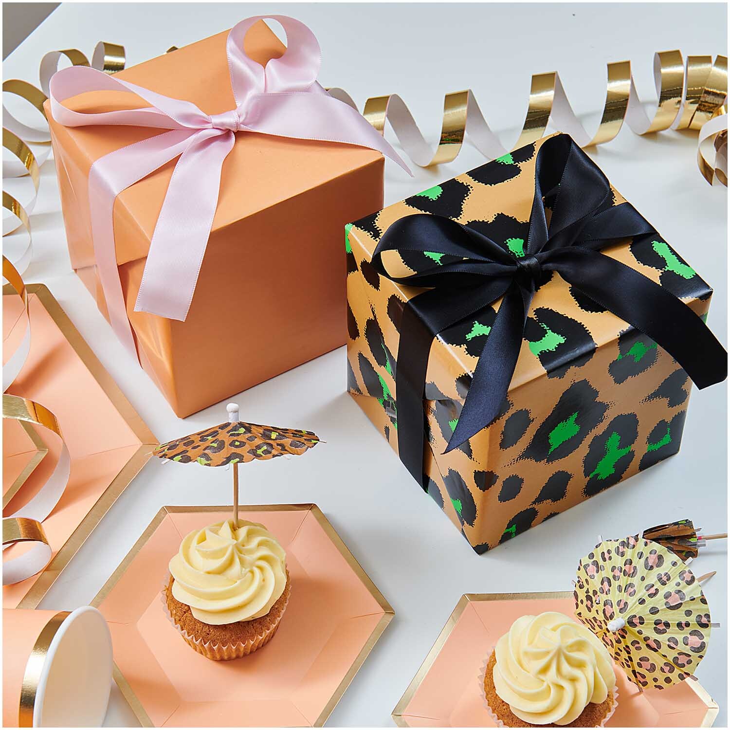 Paper Poetry Geschenkpapier Acid Leo honigfarben 70cm 3m 70g/m² von Rico Design Paper Poetry Geschenkpapier zeigt honigfarbene Schachteln mit Schleifen, umgeben von Cupcakes und Dekorationen.