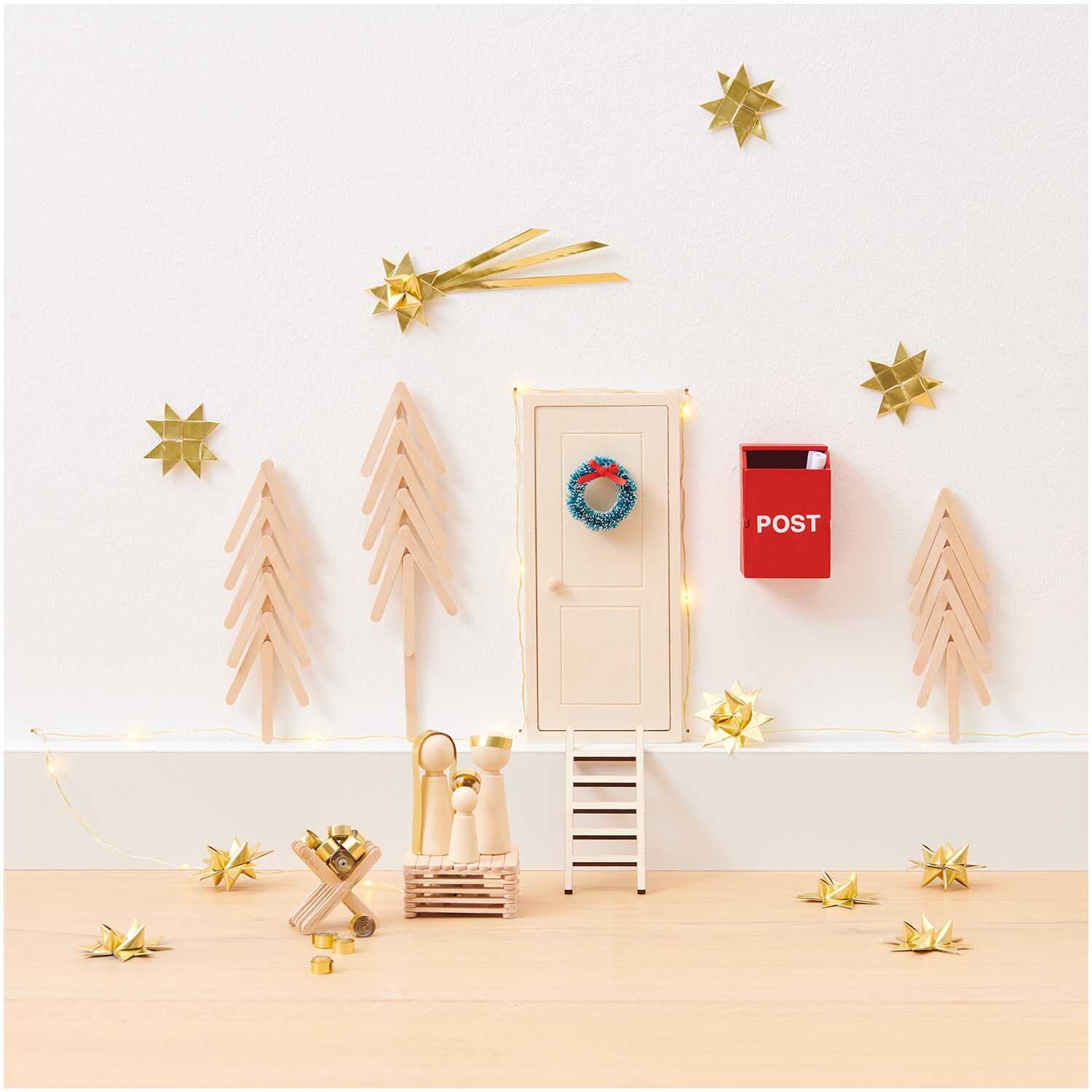 Miniatur Wichteltür mit Leiter und rotem Briefkasten, umgeben von goldenen Sternen und Bäumen.