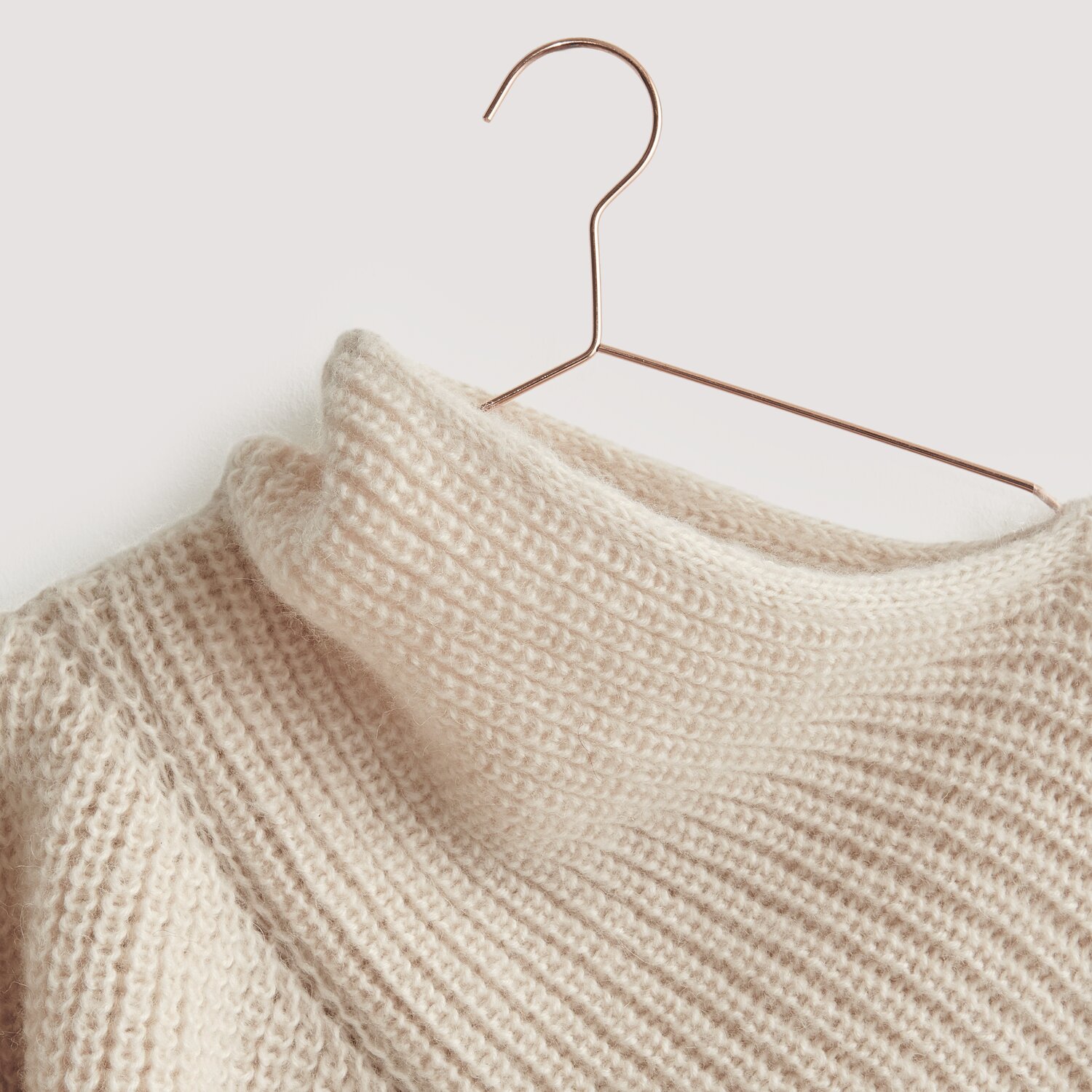Luxury Merino Alpaca Dream aran 50g 125m Farbe Creme von Rico Design Luxury Merino Alpaca Dream aran: Cremefarbener Strickpullover aus natürlichen Fasern auf Kupferbügel.