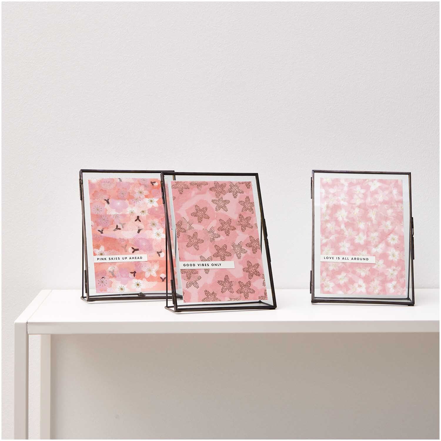 Paper Poetry Paper Patch Papier Kirschblüten Mix zeigt drei rosa Papierdesigns mit floralen Mustern in Rahmen auf einem weißen Tisch.