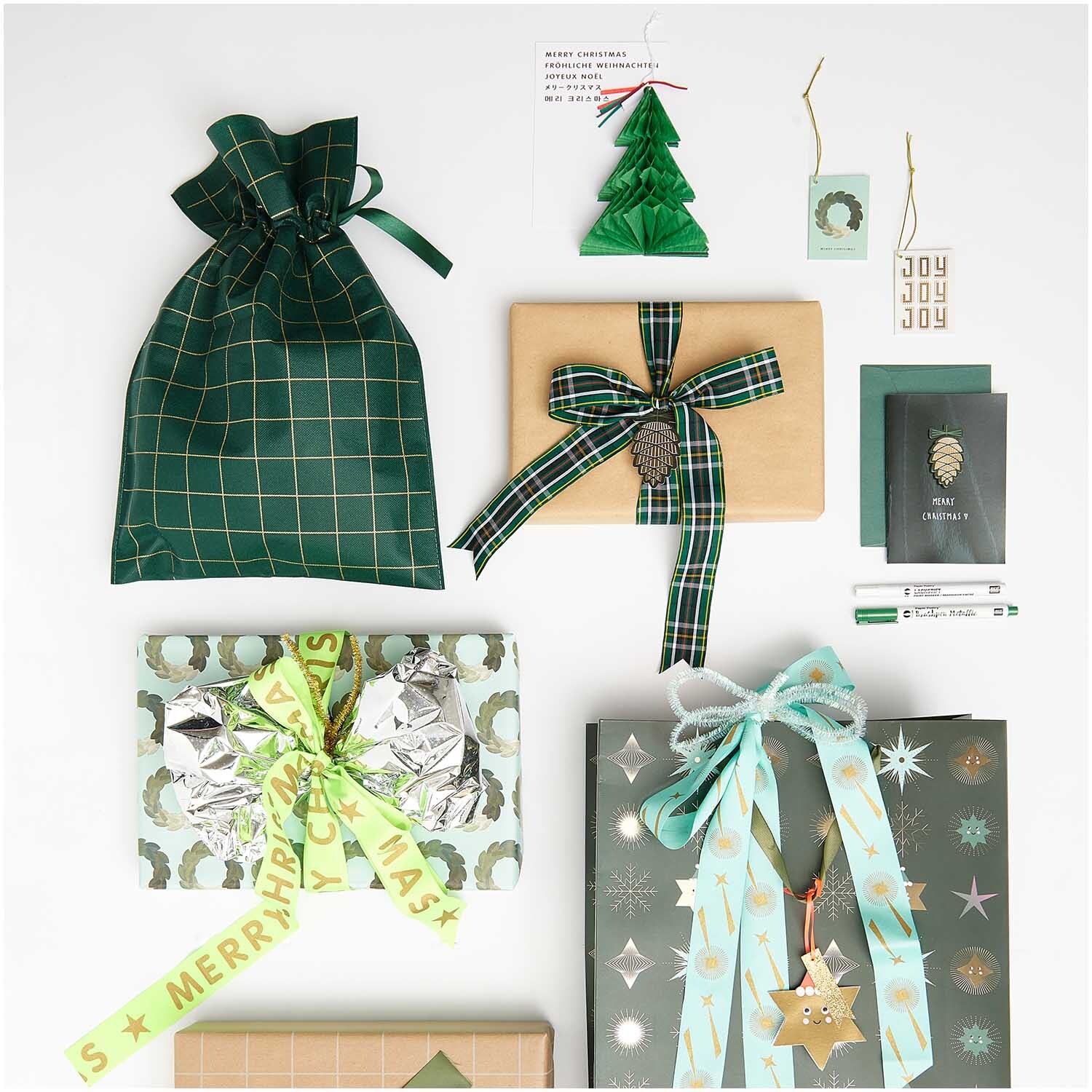 Paper Poetry Geschenktasche in grün-gold mit kariertem Muster, umgeben von festlich verpackten Geschenken und Dekorationen.