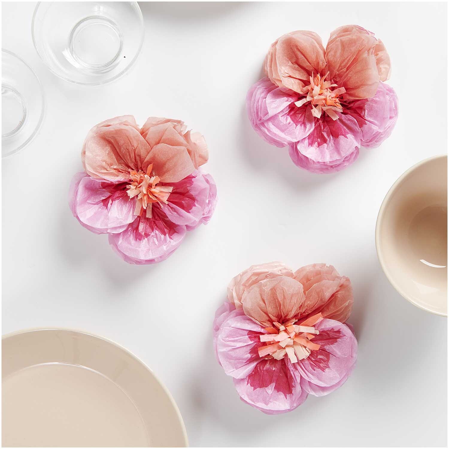 Seidenpapierblumen Stiefmütterchen von Rico Design in Pink, dekorativ arrangiert auf einem Tisch.
