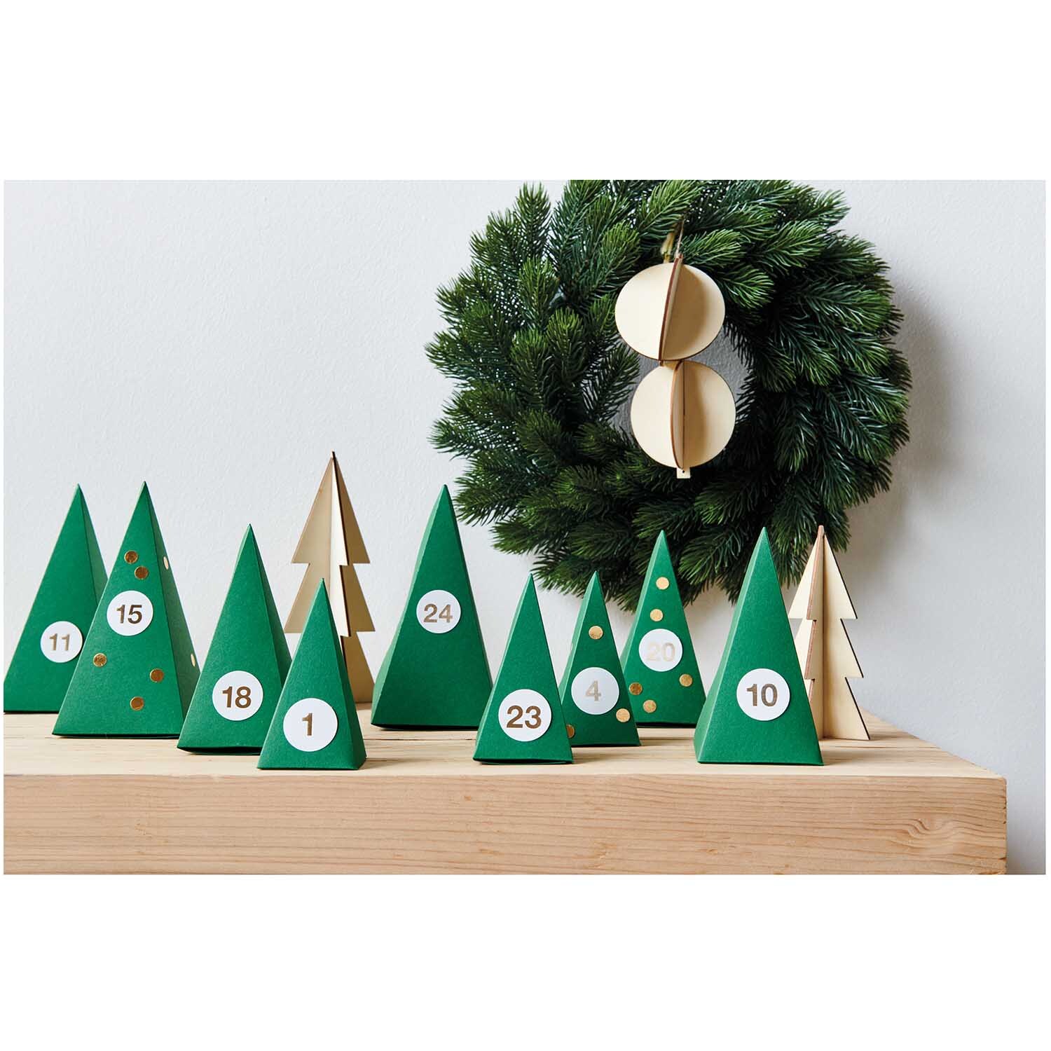 Paper Poetry Adventskalender Bäume 24 Stück Farbe Grün von Rico Design Paper Poetry Adventskalender Bäume 24 Stück: Grüne und holzfarbene Tannen auf Holzbrett, dekoriert mit Zahlen.