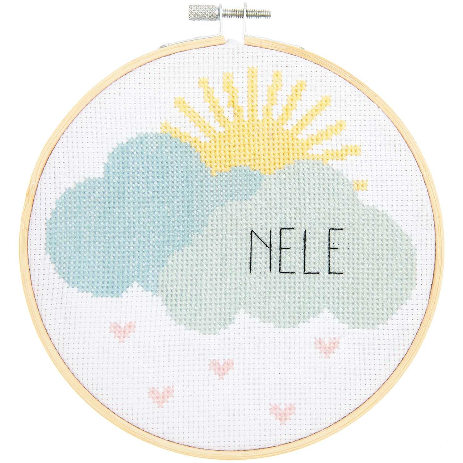 Stickpackung Geburtsbild Wolken zeigt pastellfarbene Wolken mit Sonne und Namen "Nele", von Rico Design.