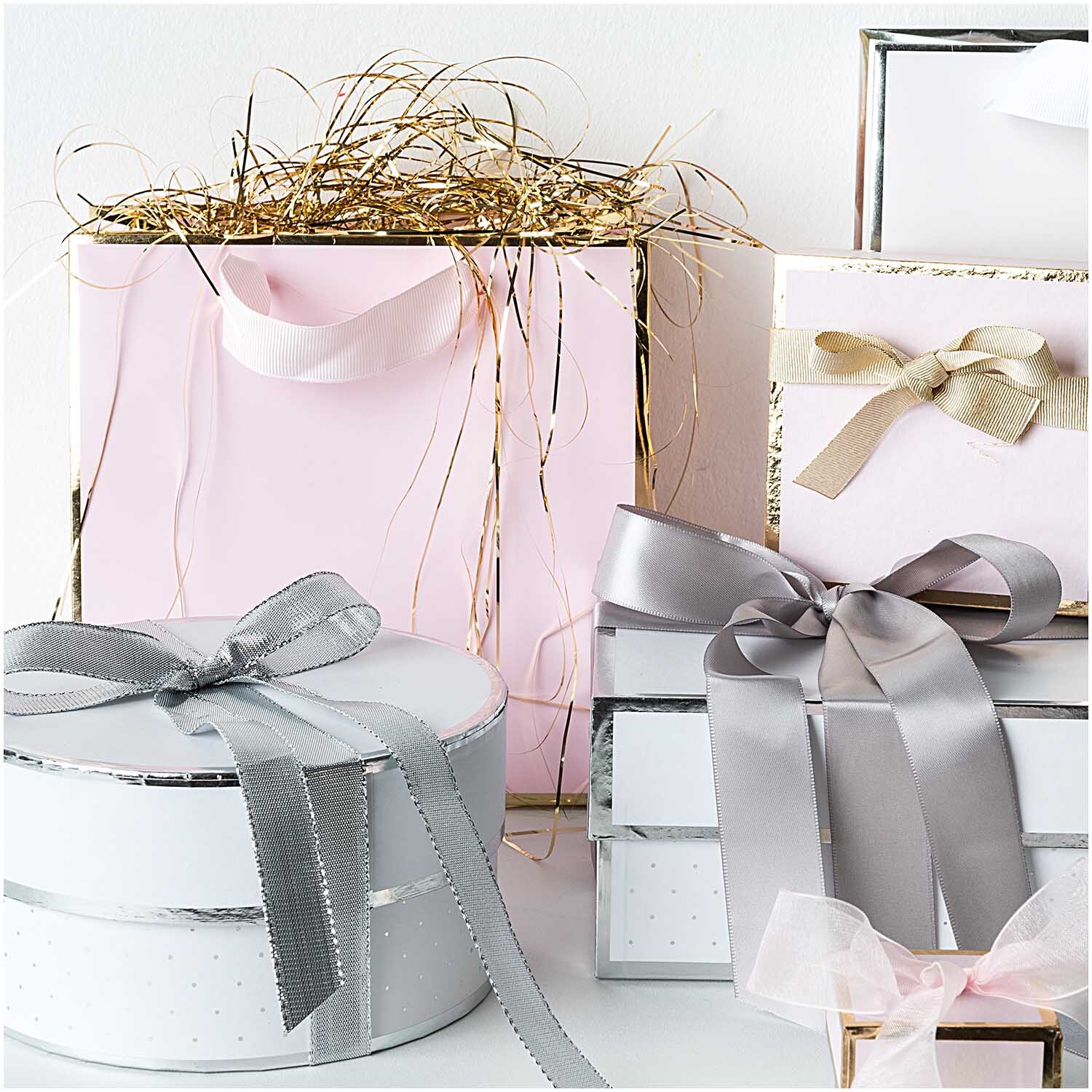 Paper Poetry Geschenkschachtel rund rosa, umgeben von eleganten Geschenkboxen mit Schleifen. Ideal für stilvolle Präsentationen.