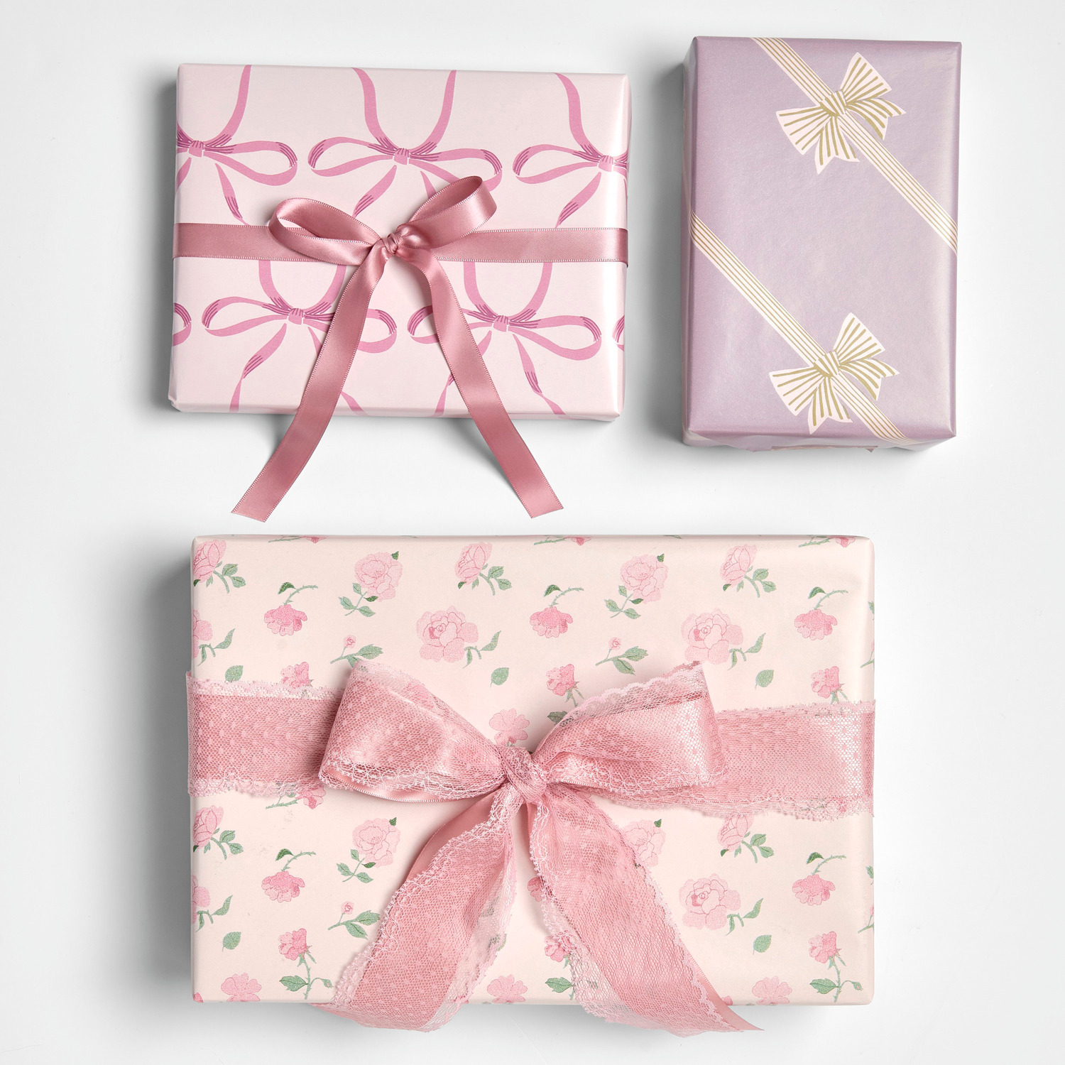 Geschenkpapier Schleifen Rosa 200x70cm 80g/m² von Rico Design Geschenkpapier Schleifen Rosa: Drei Geschenke in rosa Papier mit Schleifen- und Rosenmuster, elegant verpackt.