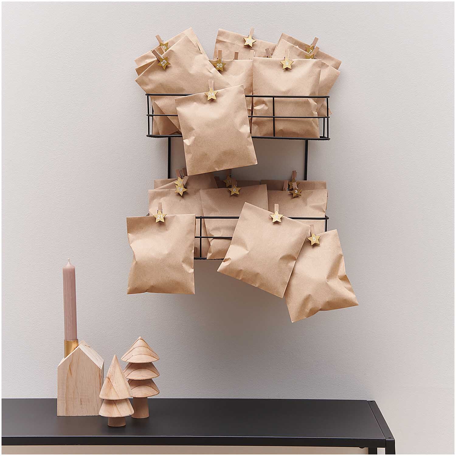 Holzclips Adventskalender Sterne 1-24 3,5cm: Adventskalender mit goldenen Sternclips von Rico Design, dekoriert an einer Wand.