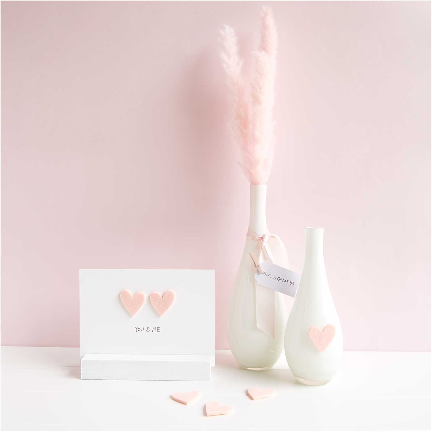Filzstreu Herz 12 Stück Farbe Rosa von Rico Design Filzstreu Herz 12 Stück: Zwei rosa Filzherzen auf weißem Hintergrund, dekoriert mit Vasen.