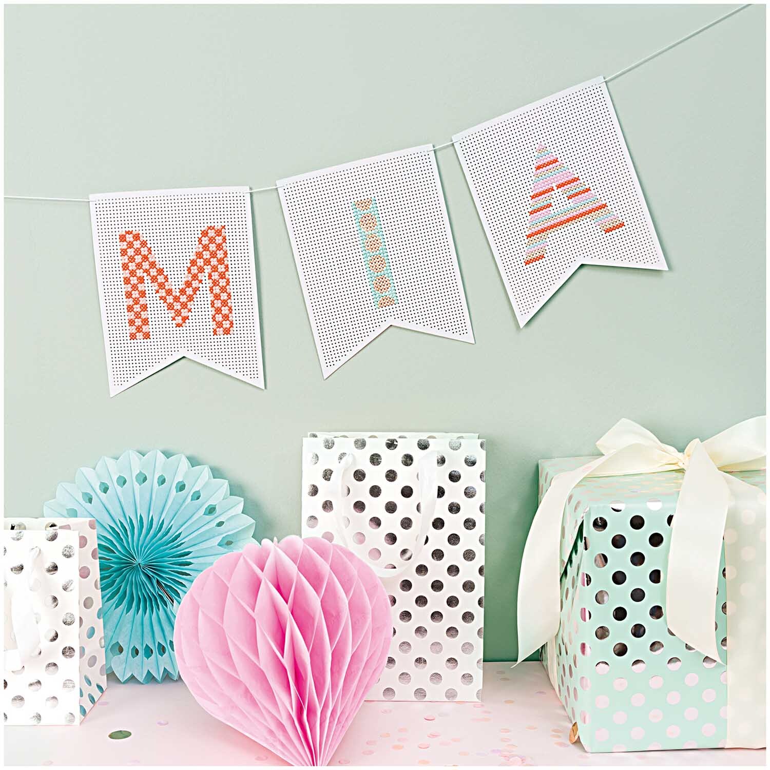 Geschenktüte weiß Punkte silber 12x18x10cm von Rico Design Geschenktüte weiß Punkte silber 12x18x10cm von Rico Design neben pastellfarbenen Dekorationen und Wimpelkette.