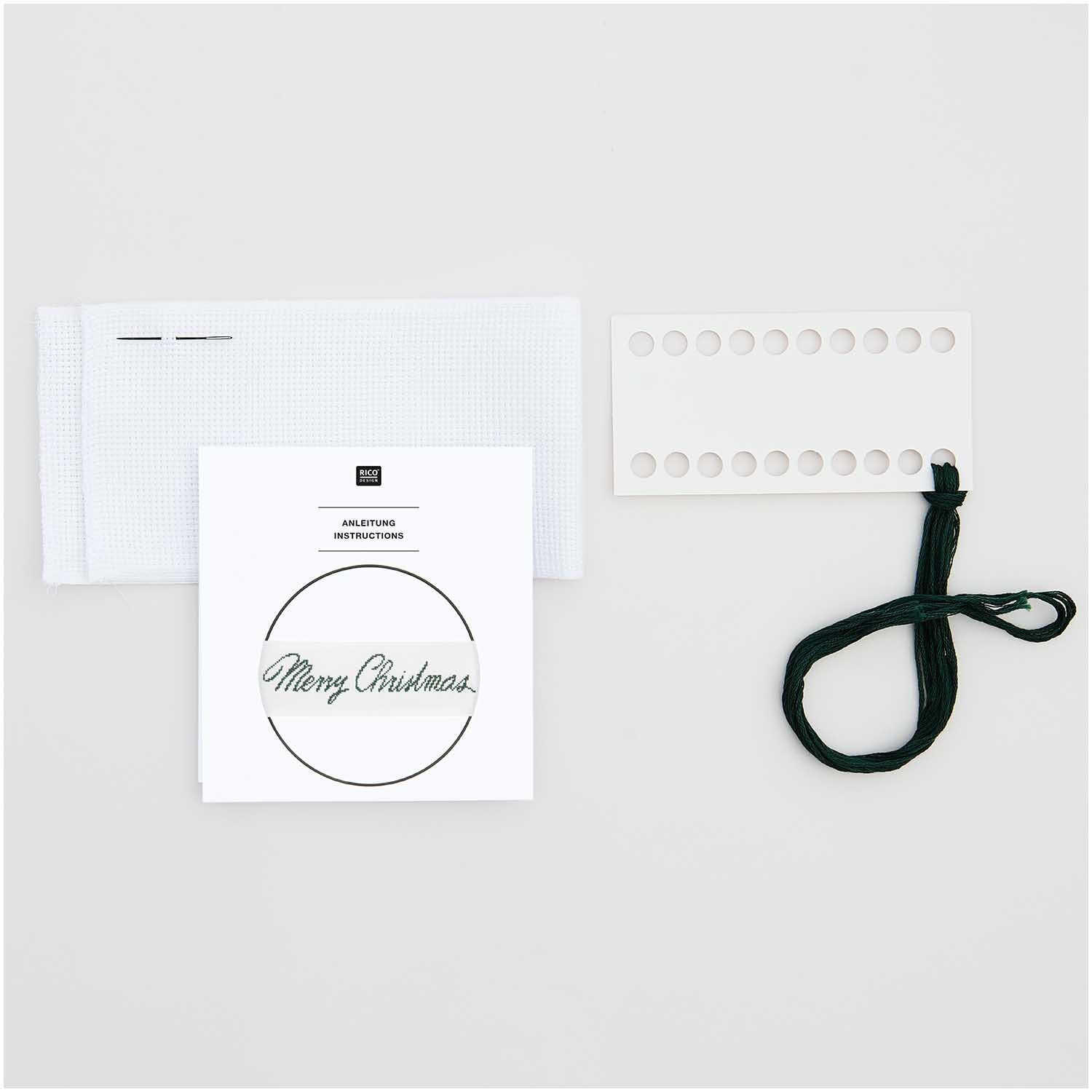 Kit de broderie ruban Frohe Weihnachten from Rico Design Stickpackung Band Frohe Weihnachten von Rico Design mit weißem Stoff, Anleitung und schwarzem Faden.