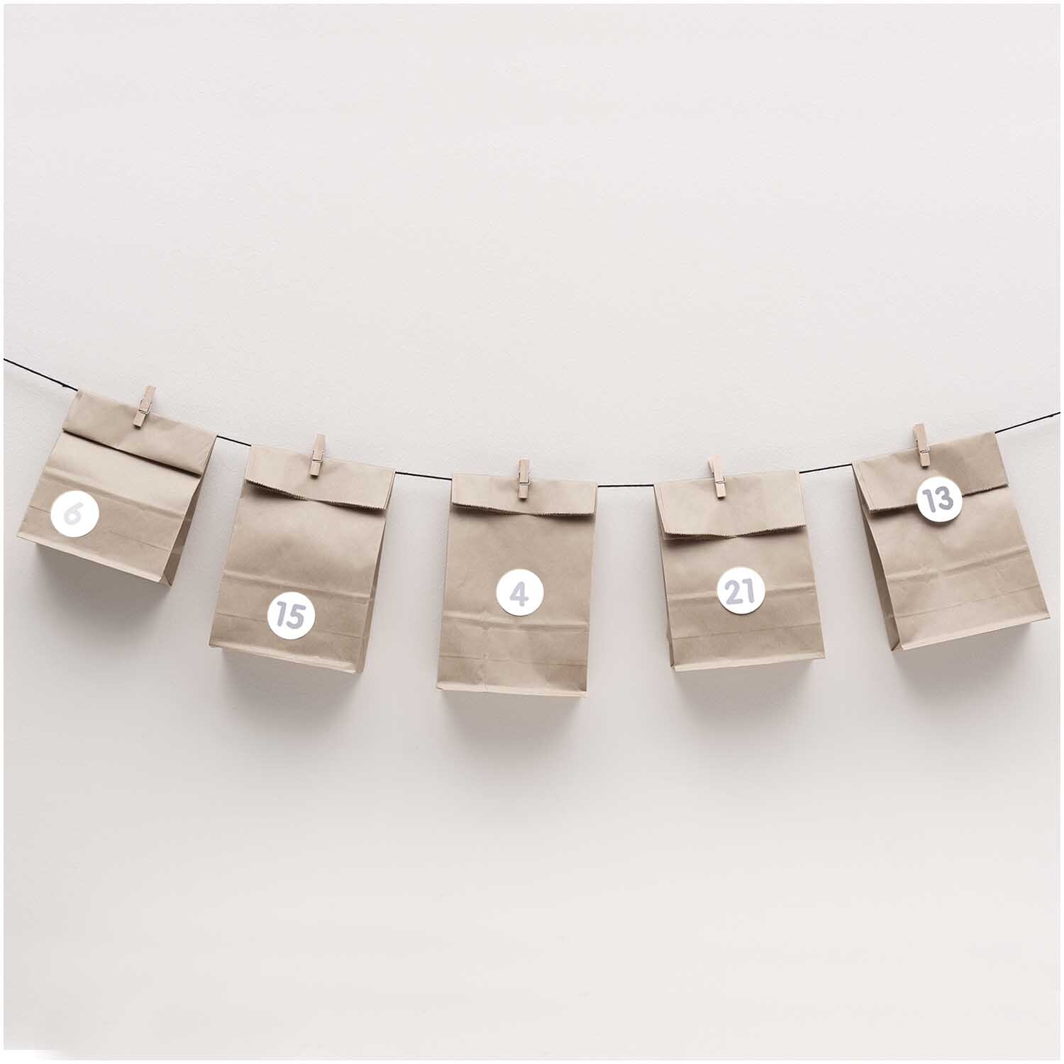 Paper Poetry Adventskalenderset mit grauen Tüten, nummeriert, an einer Leine aufgehängt.