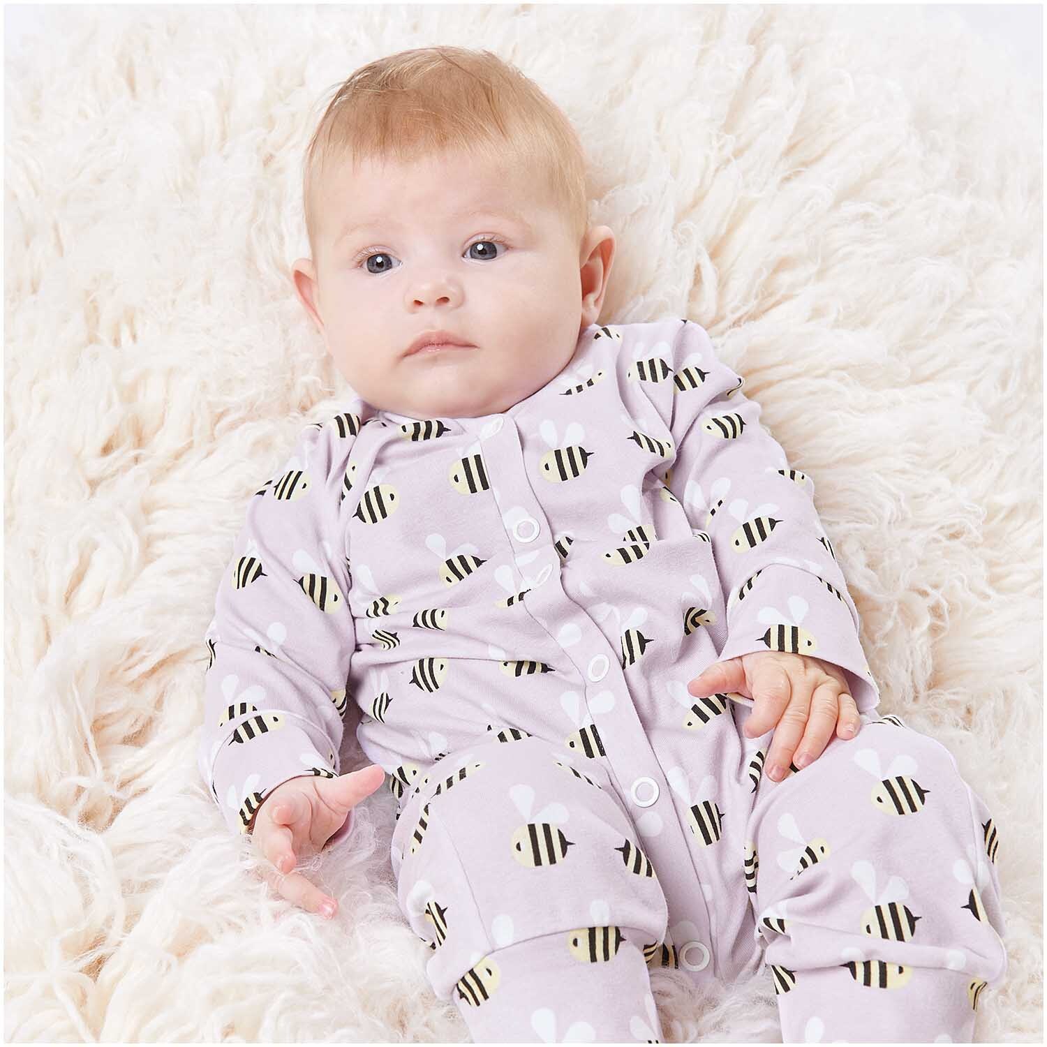Stoffabschnitt Jersey bedruckt Bienen flieder 80x100cm von Rico Design Stoffabschnitt Jersey bedruckt Bienen flieder 80x100cm: Baby in fliederfarbenem Bienen-Strampler von Rico Design auf weichem, cremefarbenem Teppich.
