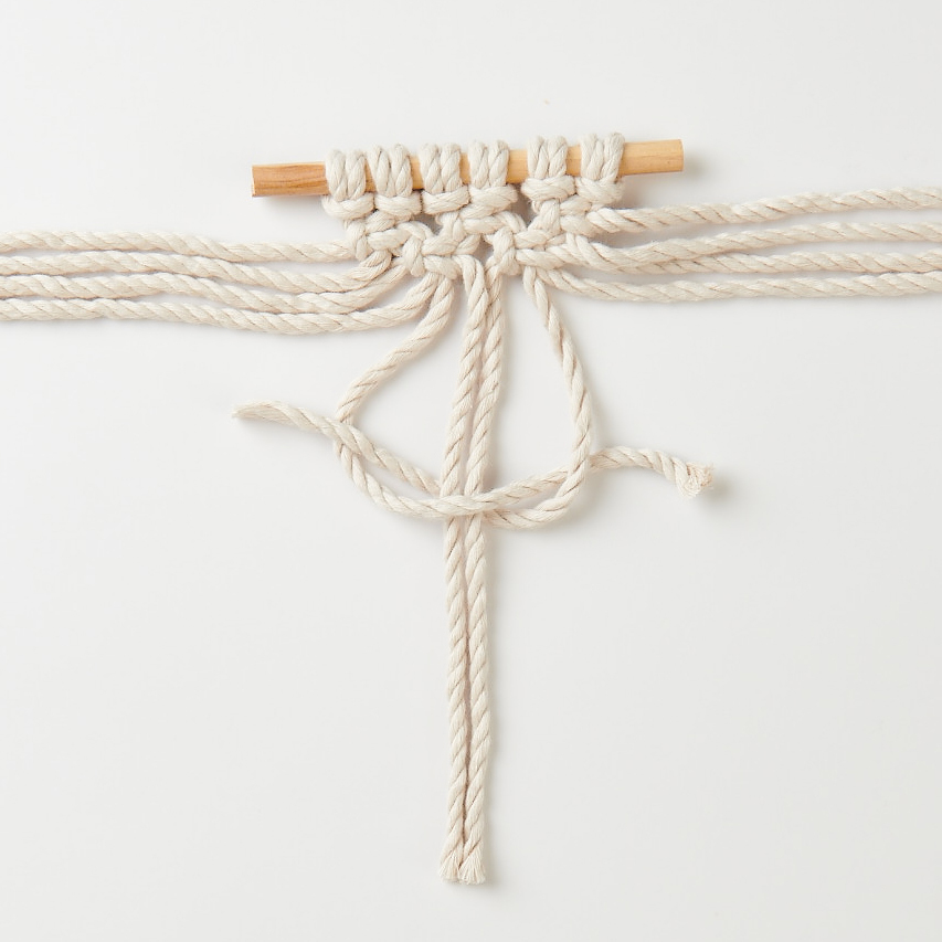 Macramé Set Tenture murale 13x13cm from Rico Design Makramee Set Wandbehang von Rico Design, zeigt ein kunstvoll geknüpftes Seilmuster auf Holzstab.