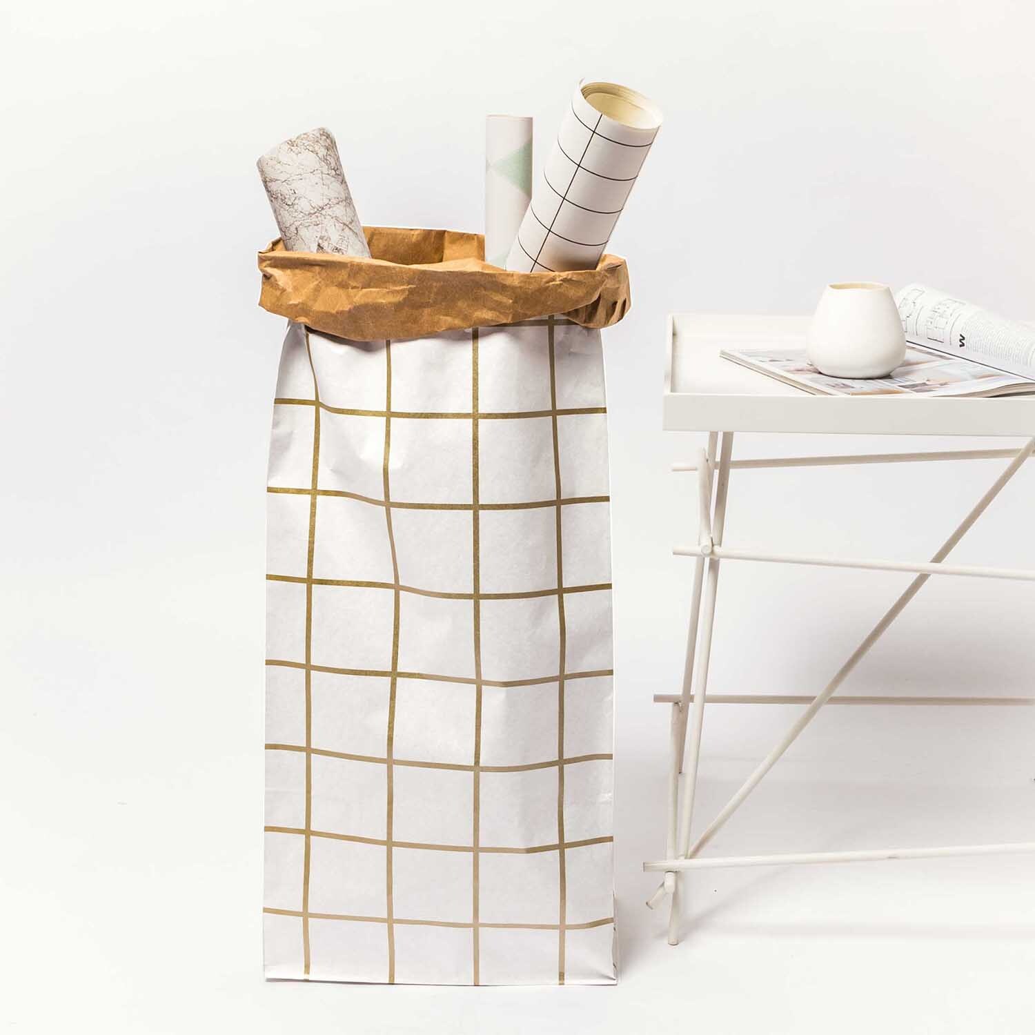 Paper Poetry Maxi-Blockbodenbeutel XL Karo 76x32x18cm 1 Stück Farbe Weiß-Braun-Gold von Rico Design Paper Poetry Maxi-Blockbodenbeutel XL Karo in Weiß-Braun-Gold neben einem weißen Tisch. Ideal zur Aufbewahrung von Rollen und Dekoration.