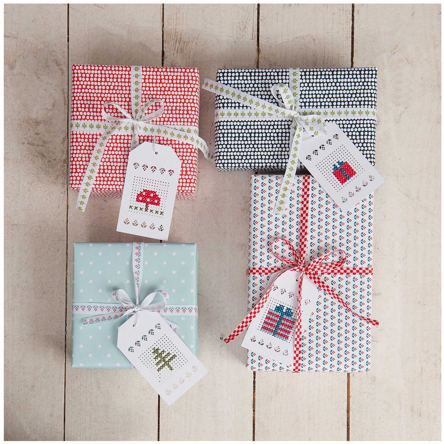 Anhänger zum Besticken creme 24 Stück von Rico Design Anhänger zum Besticken creme 24 Stück von Rico Design auf Geschenken mit buntem Papier und Stickmotiven.