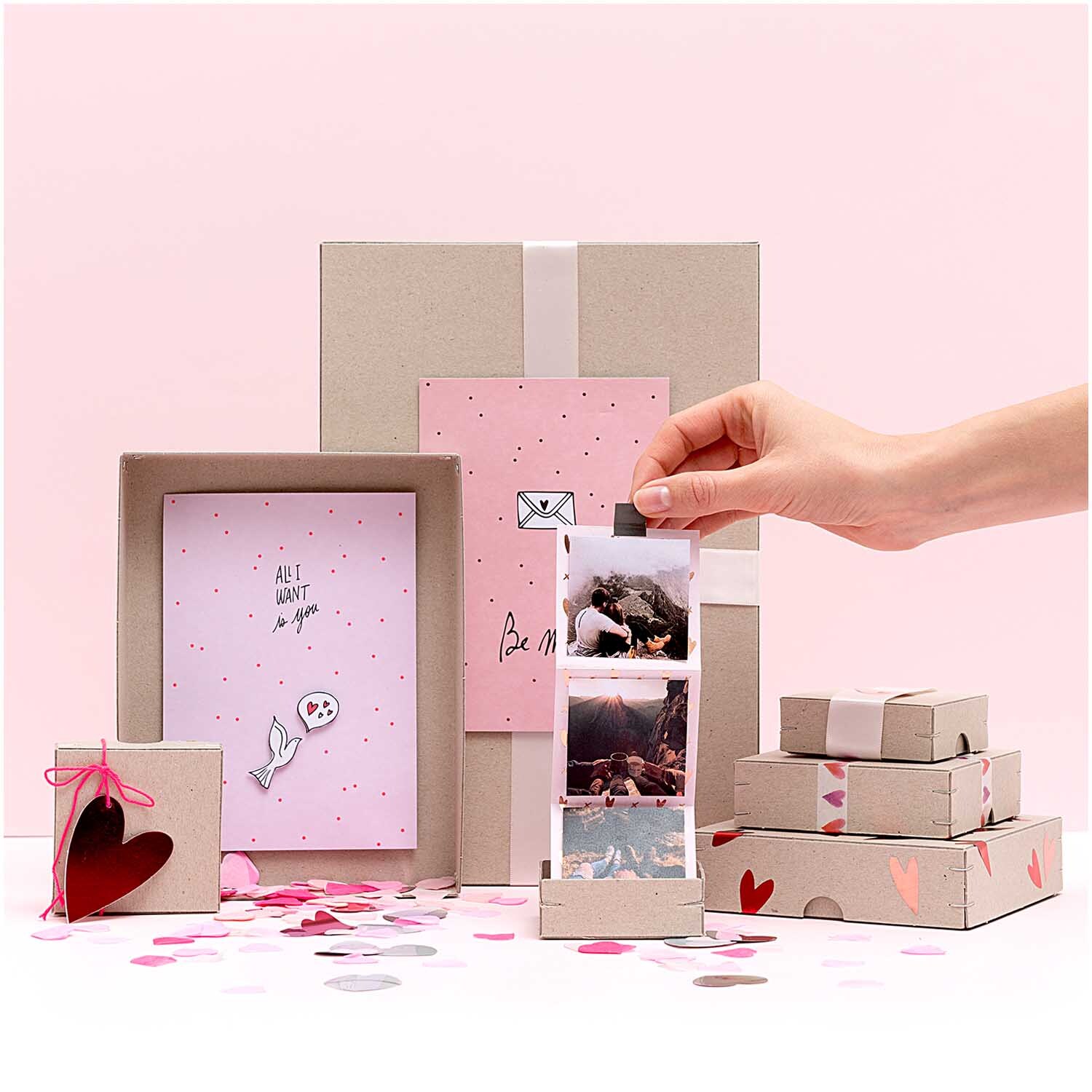 Ritzschachtel quadratisch Größe 10x10x3,5cm von Rico Design Ritzschachtel quadratisch von Rico Design in einem kreativen Arrangement mit rosa und grauen Boxen, dekoriert mit Herzen und Konfetti.
