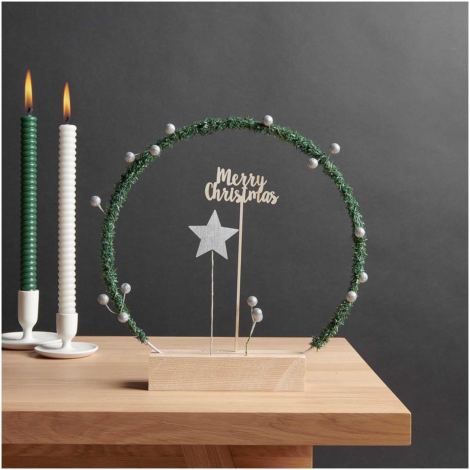Holzständer für Metallringe 18x5x4cm mit grünem Kranz und "Merry Christmas"-Schriftzug.