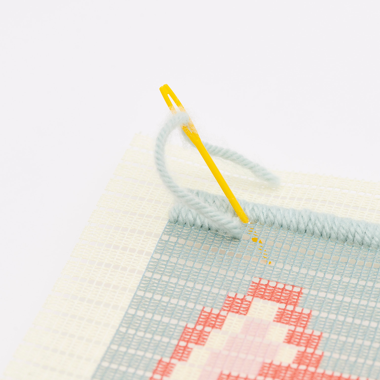 Kit de broderie Longstitch renard 18x30cm from Rico Design Longstitch Stickpackung Fuchs zeigt eine Nahaufnahme einer Sticknadel auf einem bunten Stoff.