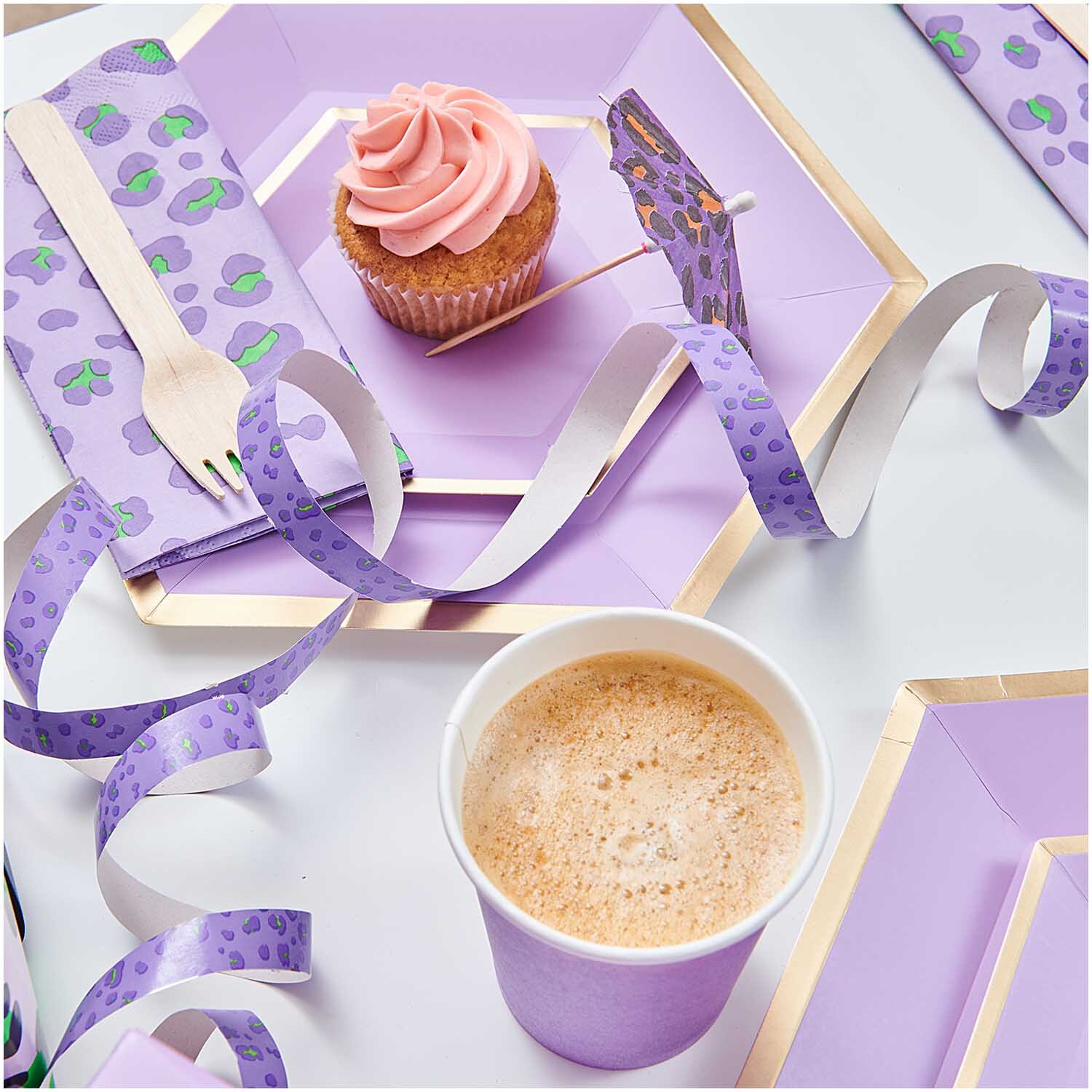 Banderoles Acid Leo argent 3,8m from Rico Design Luftschlangen Acid Leo silber 3,8m dekorieren einen Tisch mit lila Geschirr und einem Cupcake.