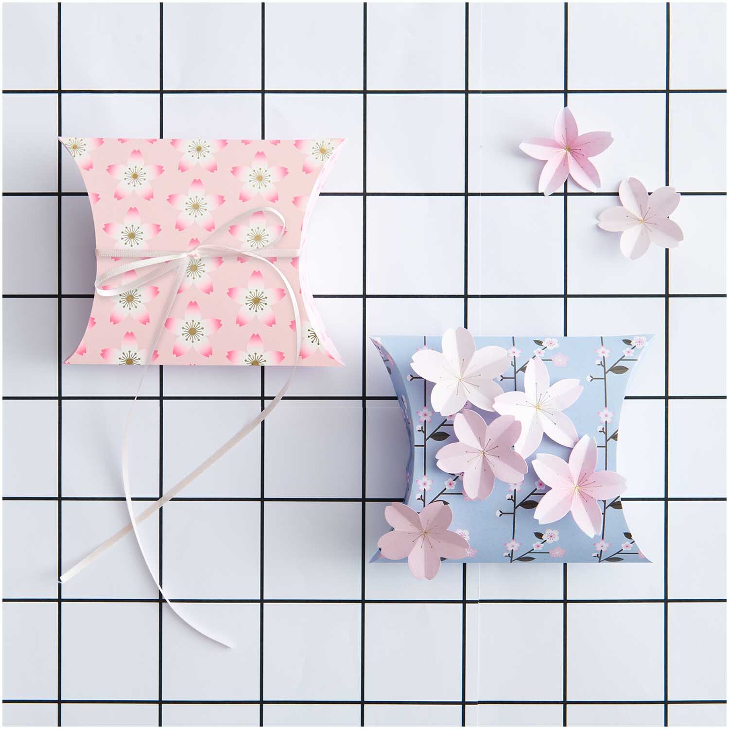 Paper Poetry Mini-Papierblüten Luxury Sakura von Rico Design auf Geschenkboxen in Rosa und Blau.
