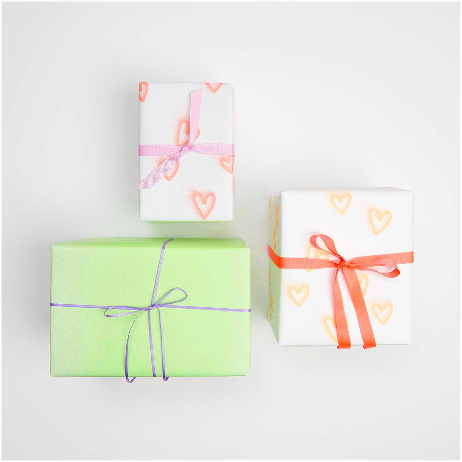 Paper Poetry Geschenkpapier Spray Herzen neon orange 200x70cm 70g/m² von Rico Design Paper Poetry Geschenkpapier zeigt weiße Pakete mit neonorangen Herzen und farbigen Schleifen.