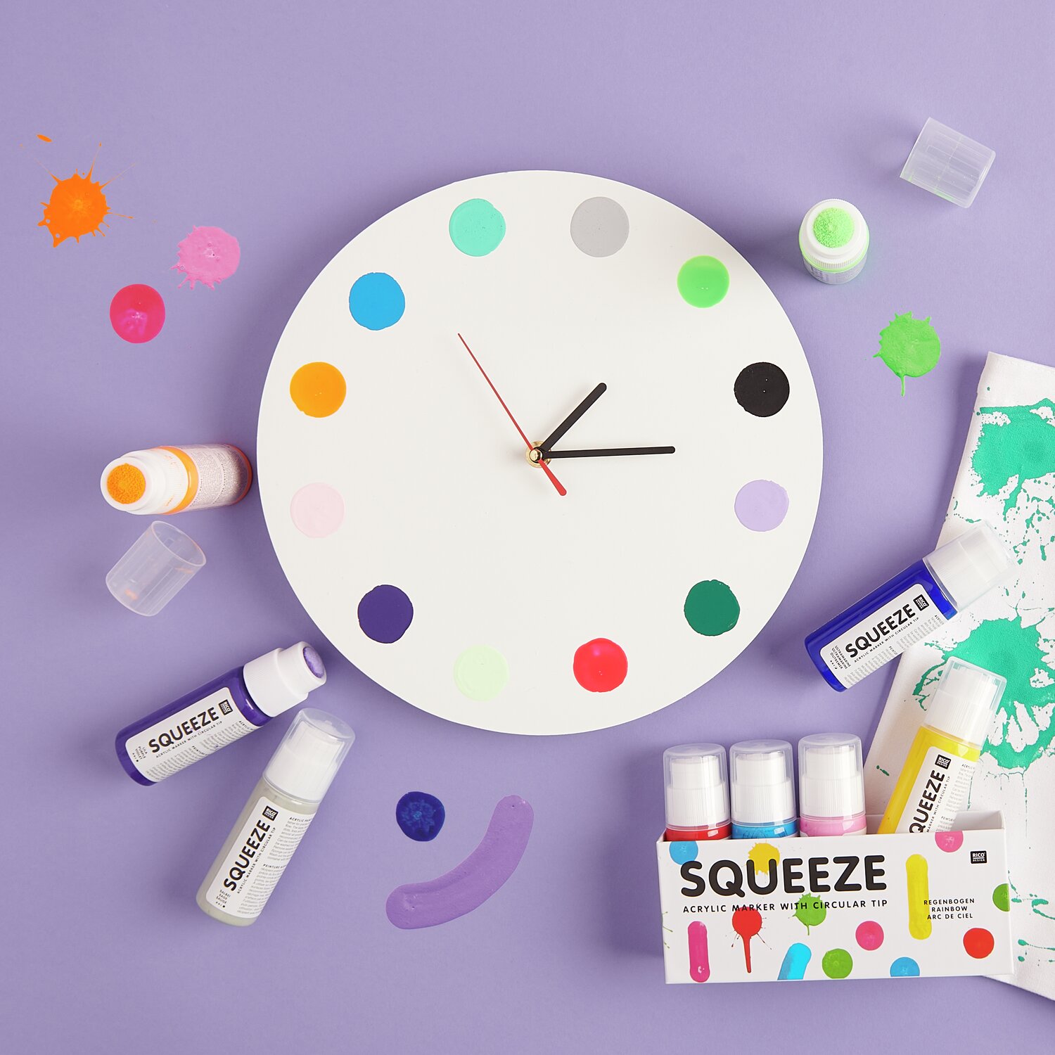 Squeeze Acrylic Marker Set Basic Rainbow 5x60ml von Rico Design Squeeze Acrylic Marker 60ml: Runde Uhr mit bunten Punkten, umgeben von Squeeze Markern auf lila Hintergrund.
