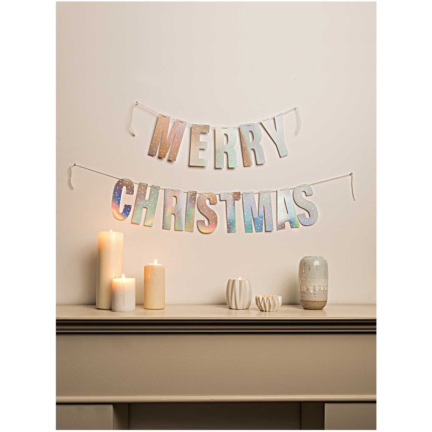 Paper Poetry Girlande Merry Christmas 3m Hot Foil Farbe Silber Irisierend von Rico Design Paper Poetry Girlande Merry Christmas 3m Hot Foil: Dekorative silberne Girlande von Rico Design, aufgehängt über einem Tisch mit Kerzen.