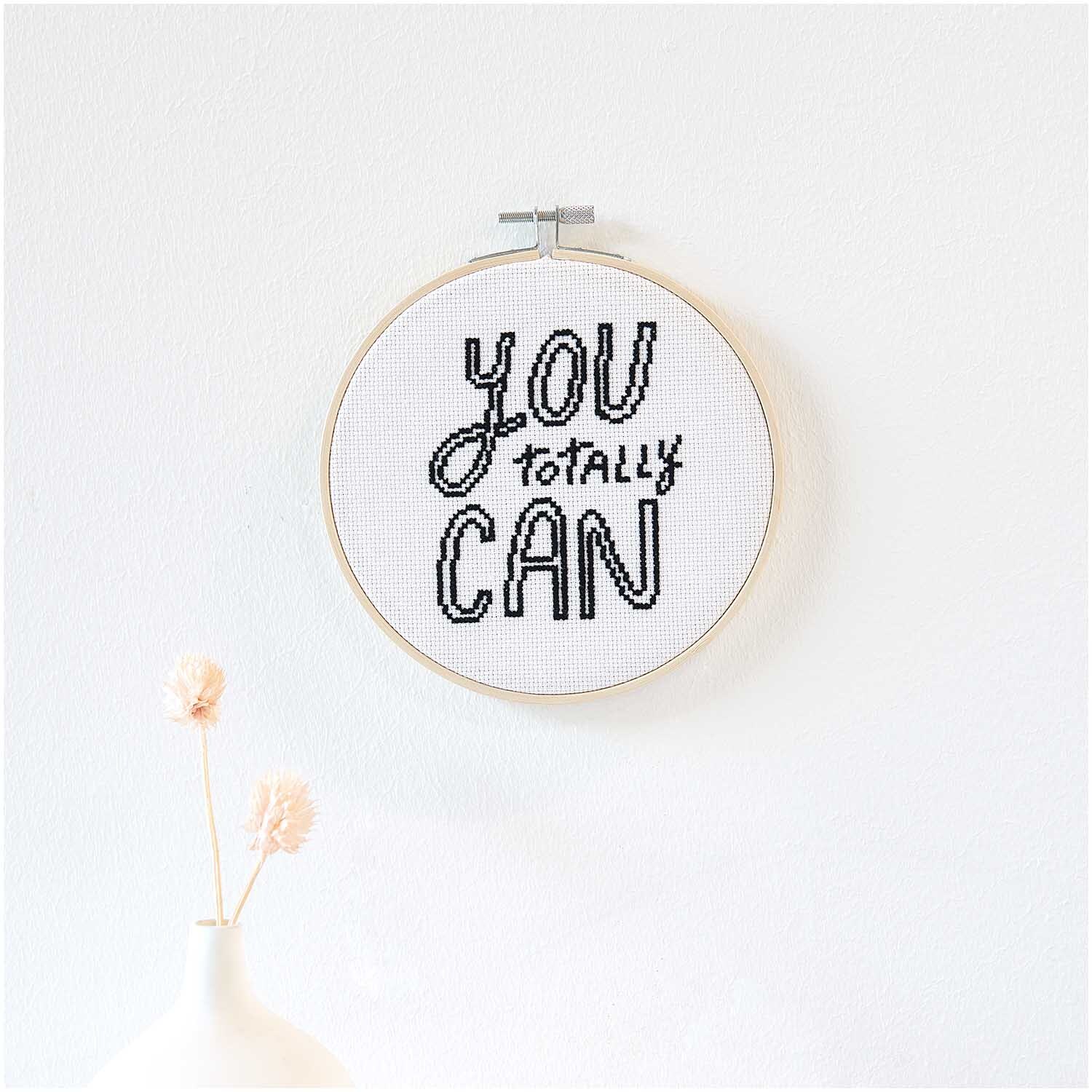 Stickpackung Bild You Totally Can Ø15cm von Rico Design zeigt eine bestickte Botschaft in einem Holzrahmen an einer weißen Wand.