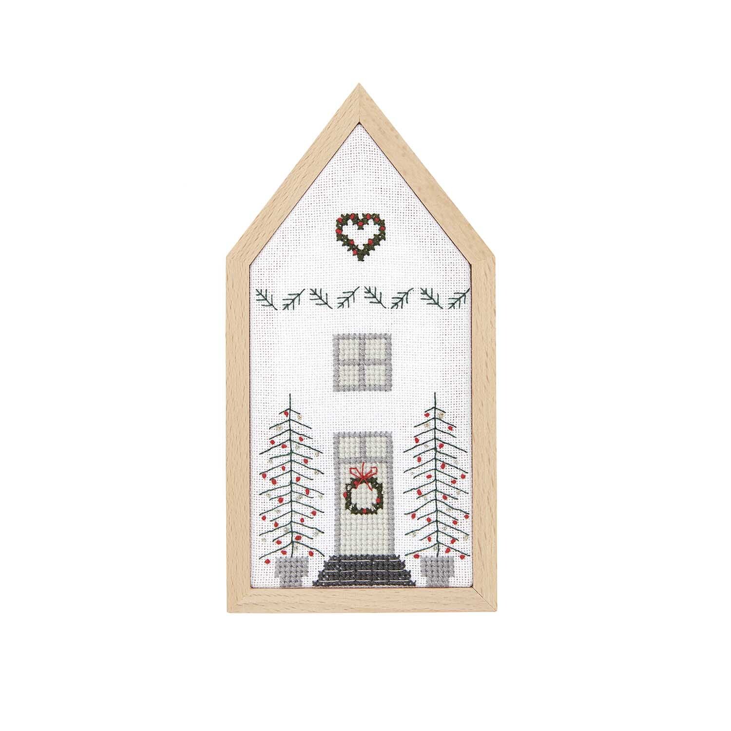 Stickpackung Haus klein 9x18cm zeigt ein gesticktes Haus mit Herzmotiv und Tannenbäumen.
