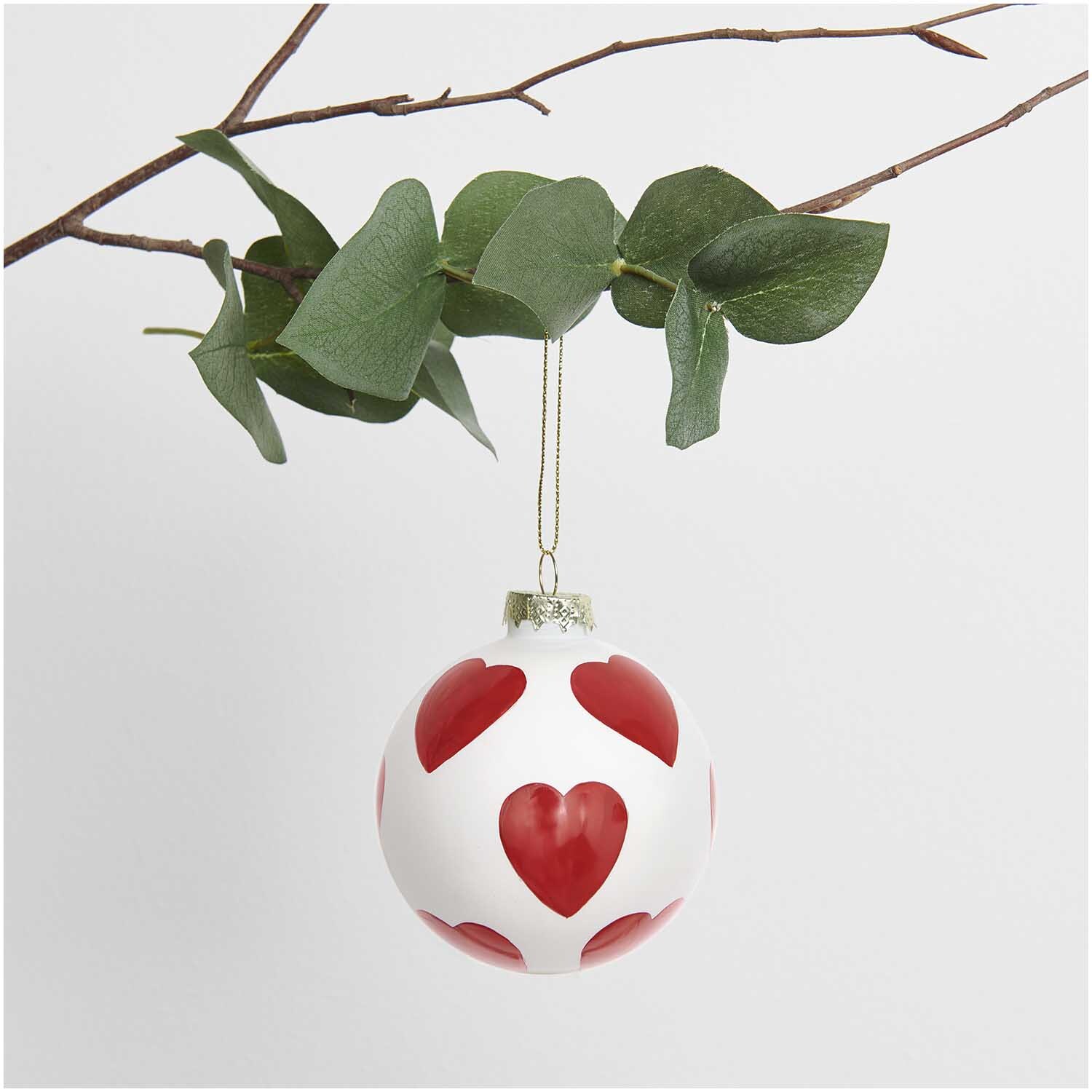 Glaskugel Baumschmuck Herz rot Ø 8cm von Rico Design Glaskugel Baumschmuck in Herzform, hängend an einem Ast mit grünen Blättern, von Rico Design.