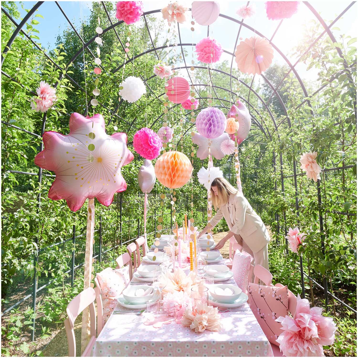 Seidenpapierblumen Kirschblüten von Rico Design schmücken einen festlich gedeckten Tisch im Garten mit rosa und weißen Dekorationen.