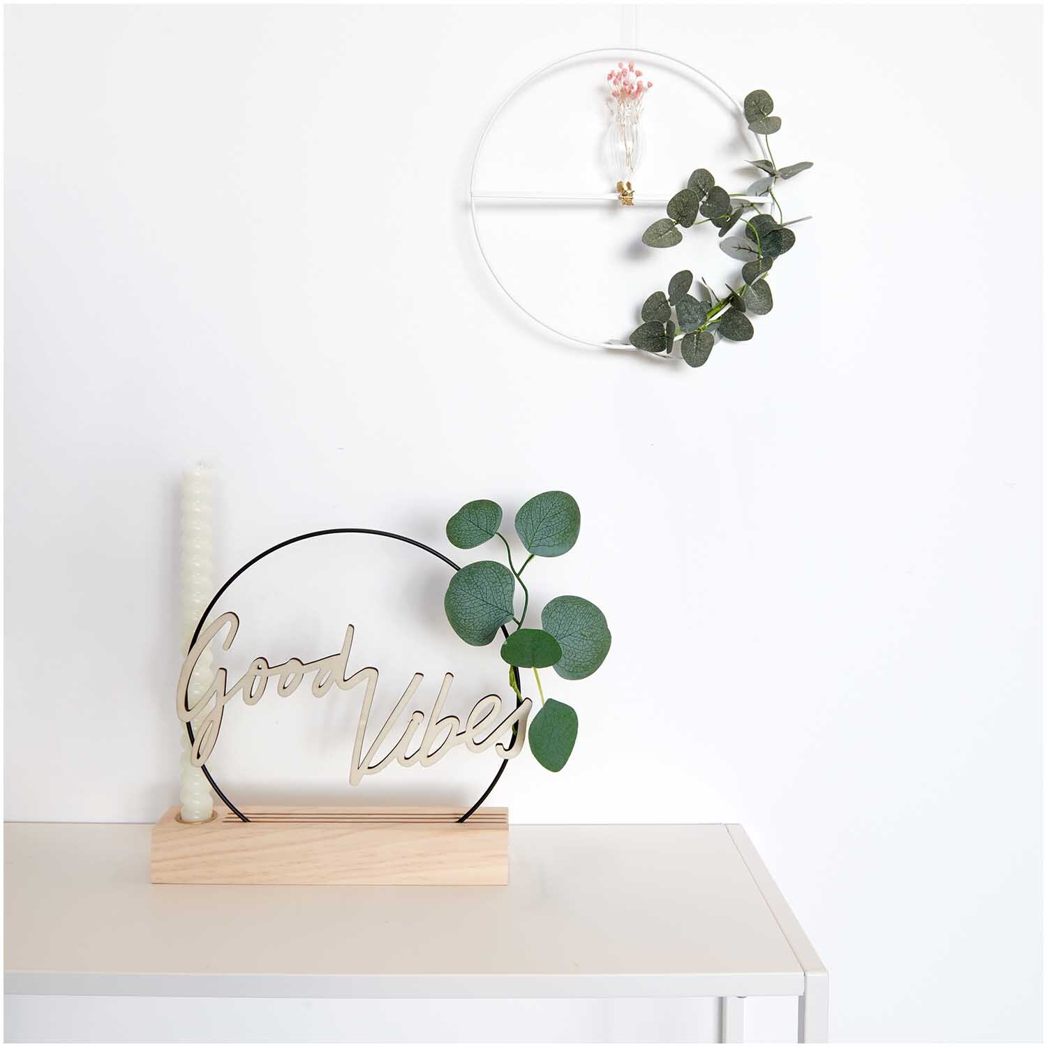 Metallring mit Querstrebe Ø25cm von Rico Design, dekoriert mit Eukalyptus und Blumen an einer weißen Wand.