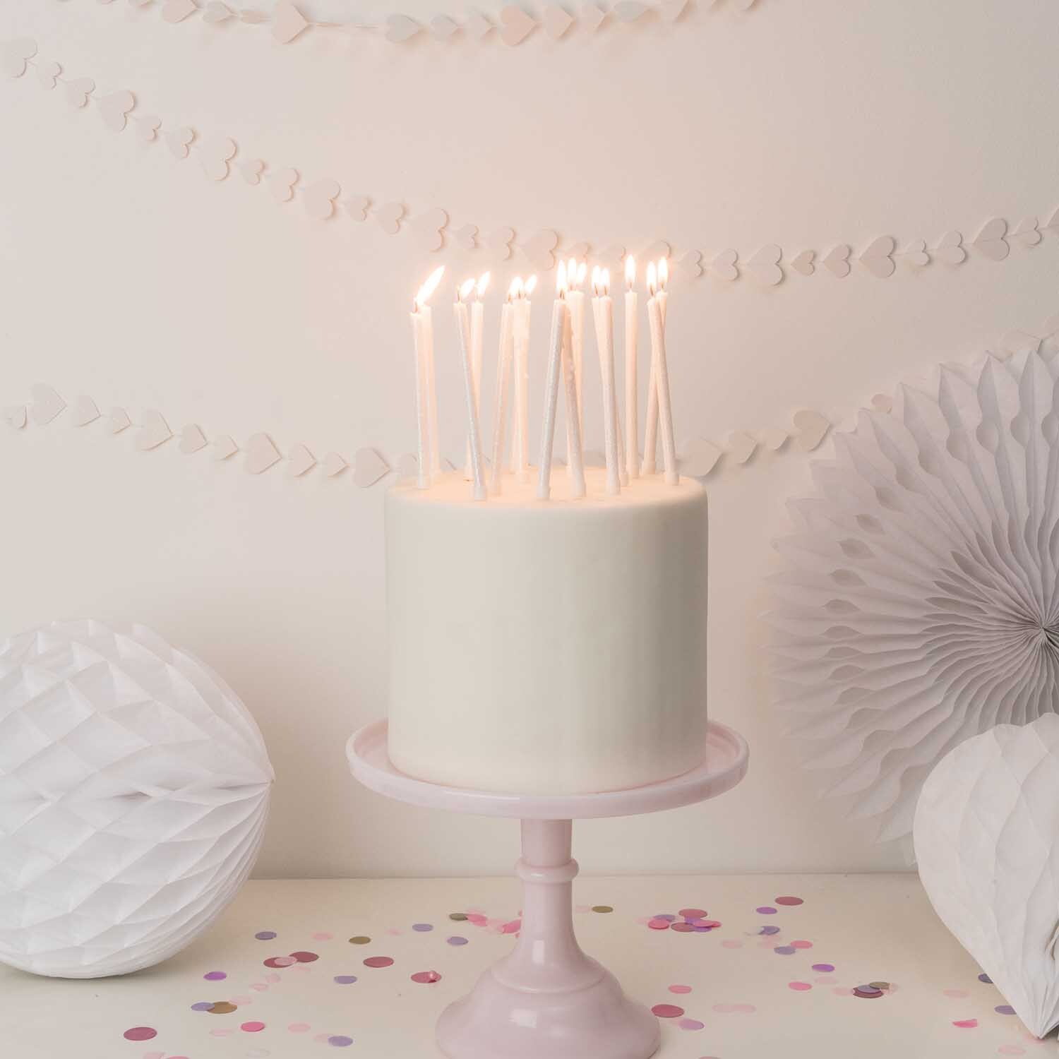Kerzen lang 16 Stück auf einer weißen Torte mit glitzernden Details, dekoriert für eine Feier.