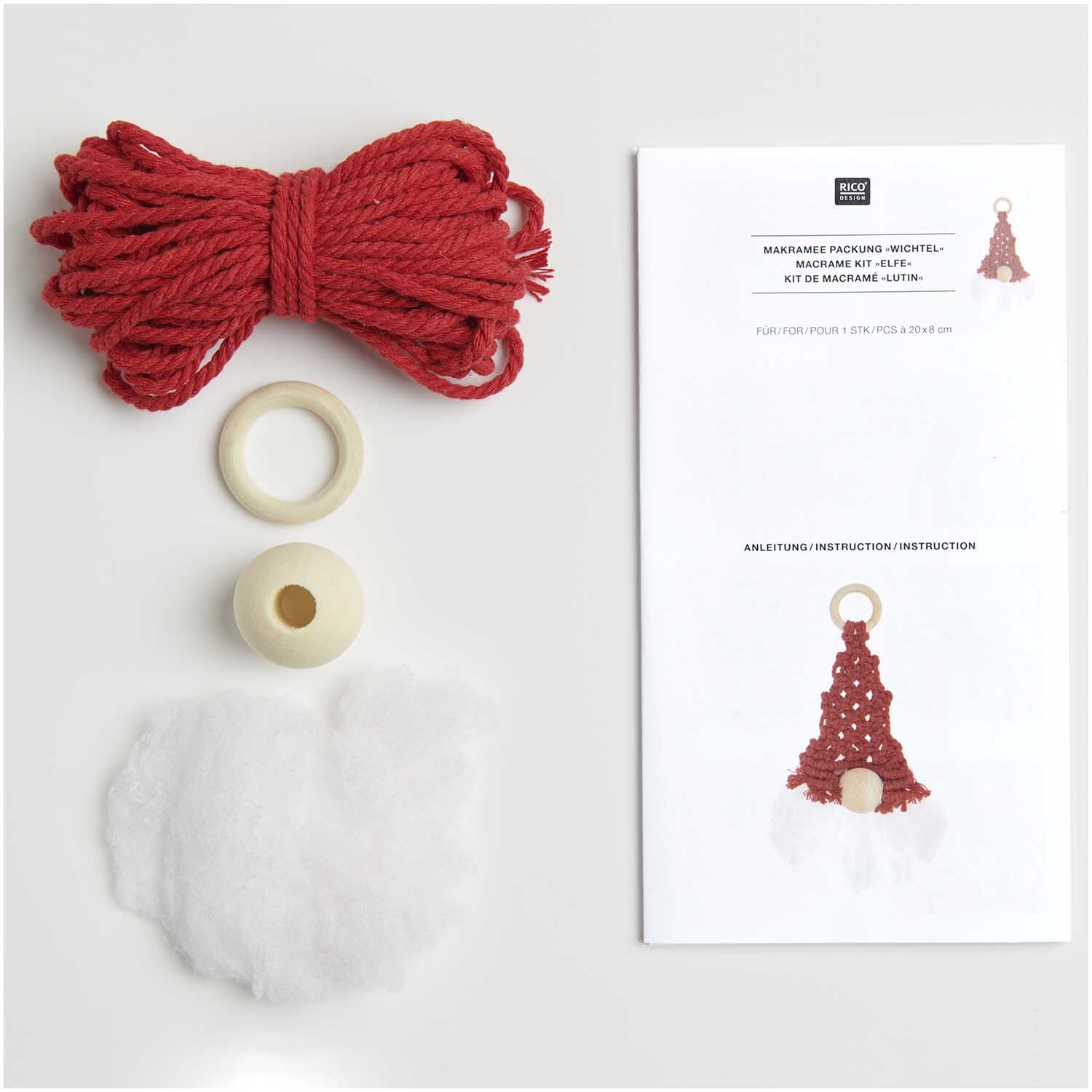 Set macramé lutin 20x8cm from Rico Design Makramee Set Wichtel 20x8cm von Rico Design mit rotem Garn, Holzringen und Anleitung auf weißem Hintergrund.