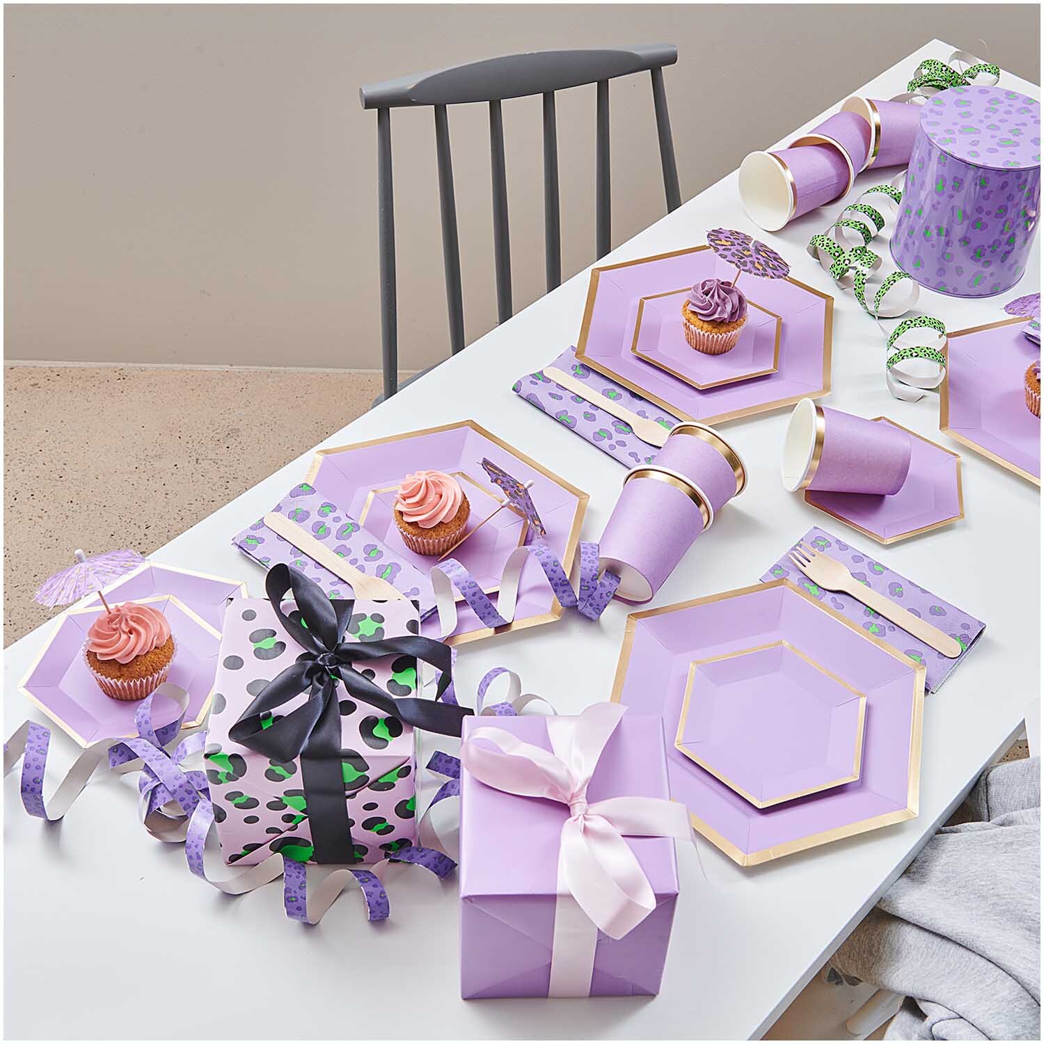 Banderoles Acid Leo argent 3,8m from Rico Design Luftschlangen Acid Leo silber 3,8m: Ein festlich gedeckter Tisch mit lila Geschirr, Geschenken und Cupcakes.