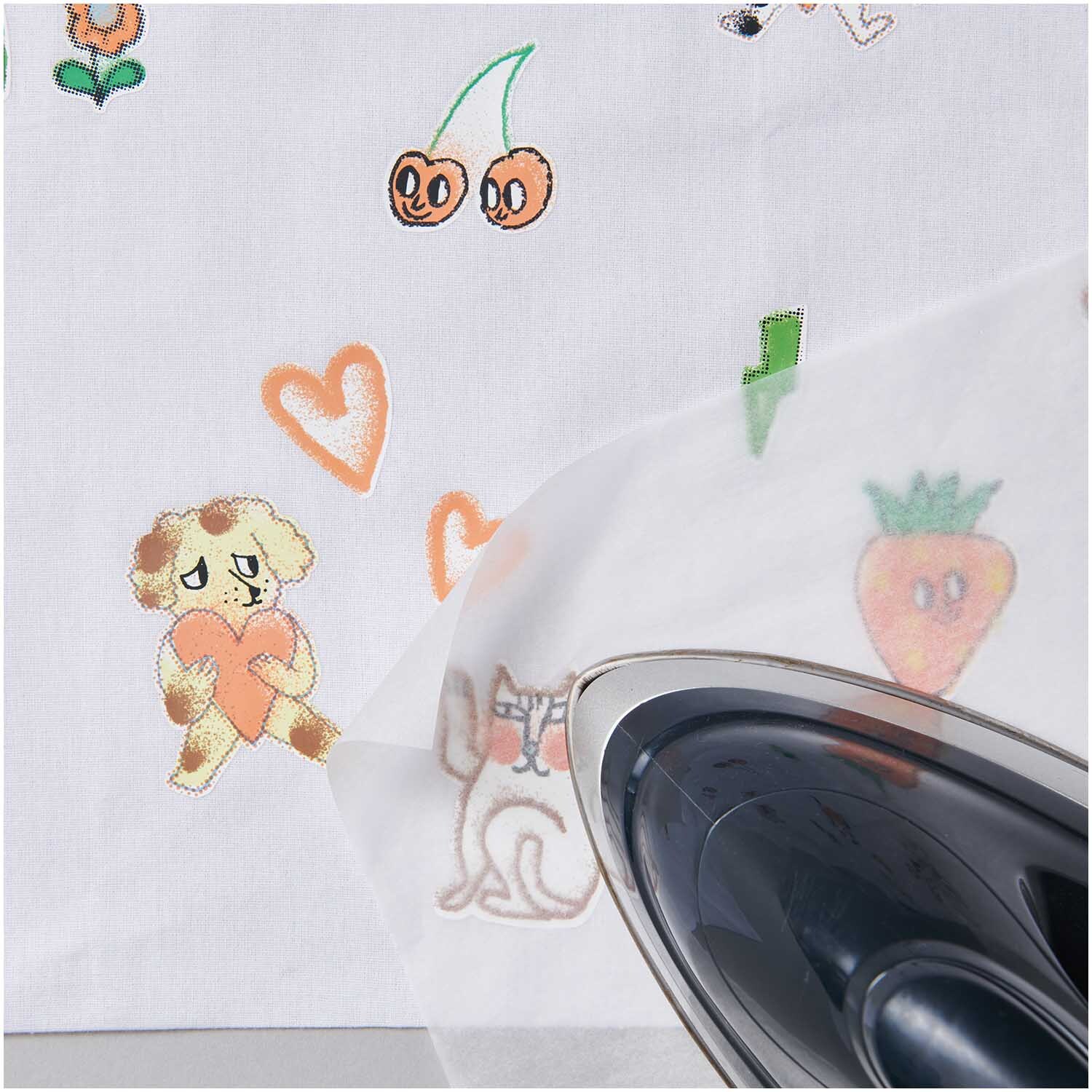 Bügelmotiv Airbrush 15 Stück: Ein Bügeleisen überträgt bunte Motive wie Herzen und Tiere auf Stoff. Ideal für kreative Textilgestaltung.