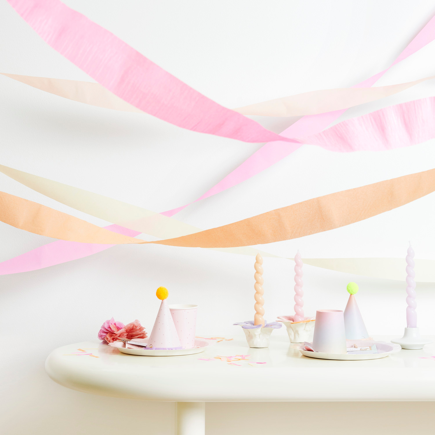 Kreppbänder extra breit Blüten Mix 5,5cmx10m 9 Stück von Rico Design Kreppbänder extra breit Blüten Mix dekorieren einen Tisch mit pastellfarbenen Kerzen und Partyhüten.