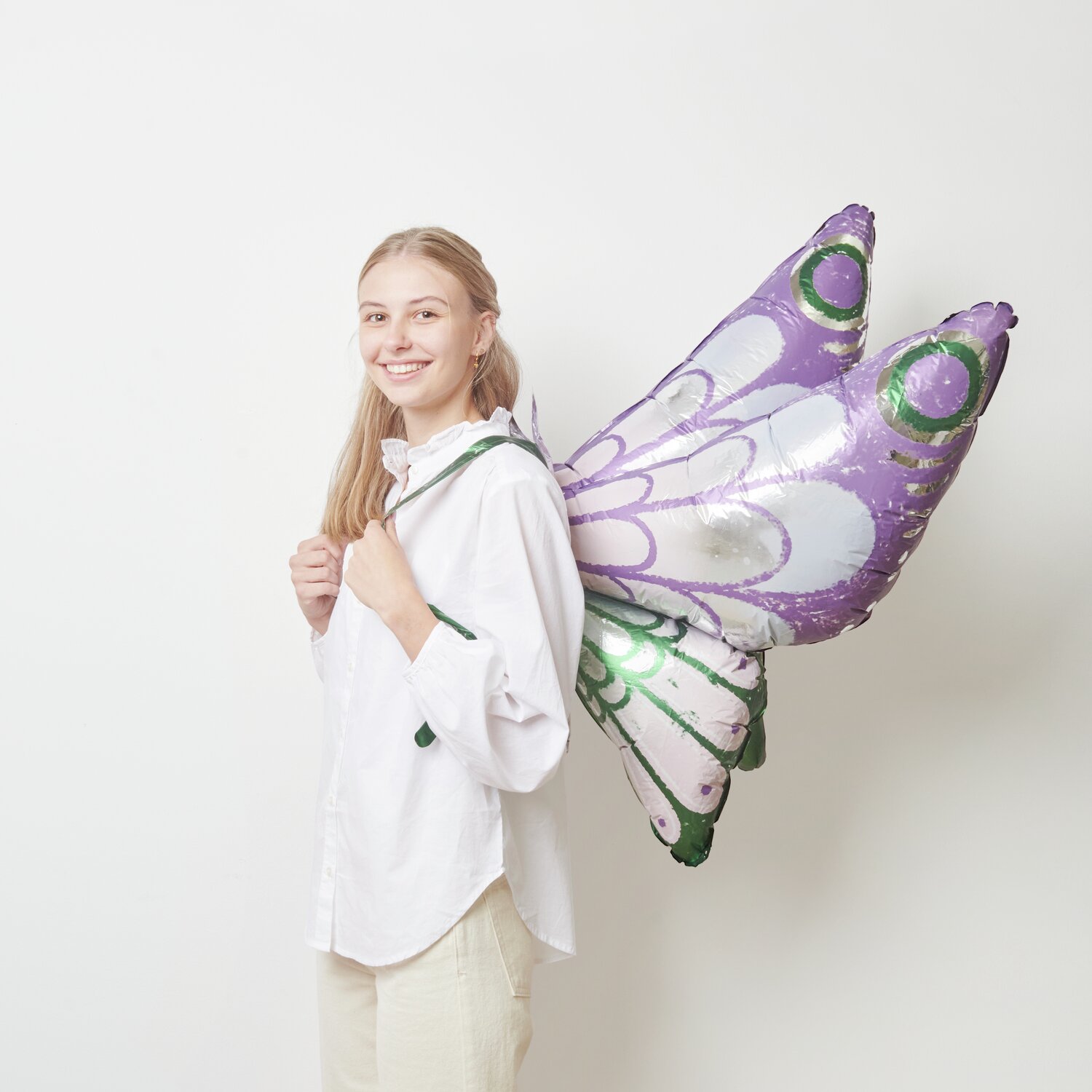 Folienballon Schmetterling zum Umbinden Lila/Grün 110x73cm von Rico Design Folienballon Schmetterling zum Umbinden in Lila-Grün von Rico Design, getragen von einer Person.