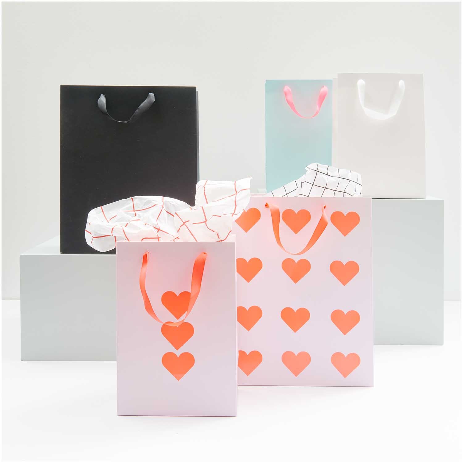 Paper Poetry Geschenktüte rosa 18x26x12cm von Rico Design Paper Poetry Geschenktüte mit Herzmuster, umgeben von weiteren Tüten in verschiedenen Farben. Ideal für Geschenke.