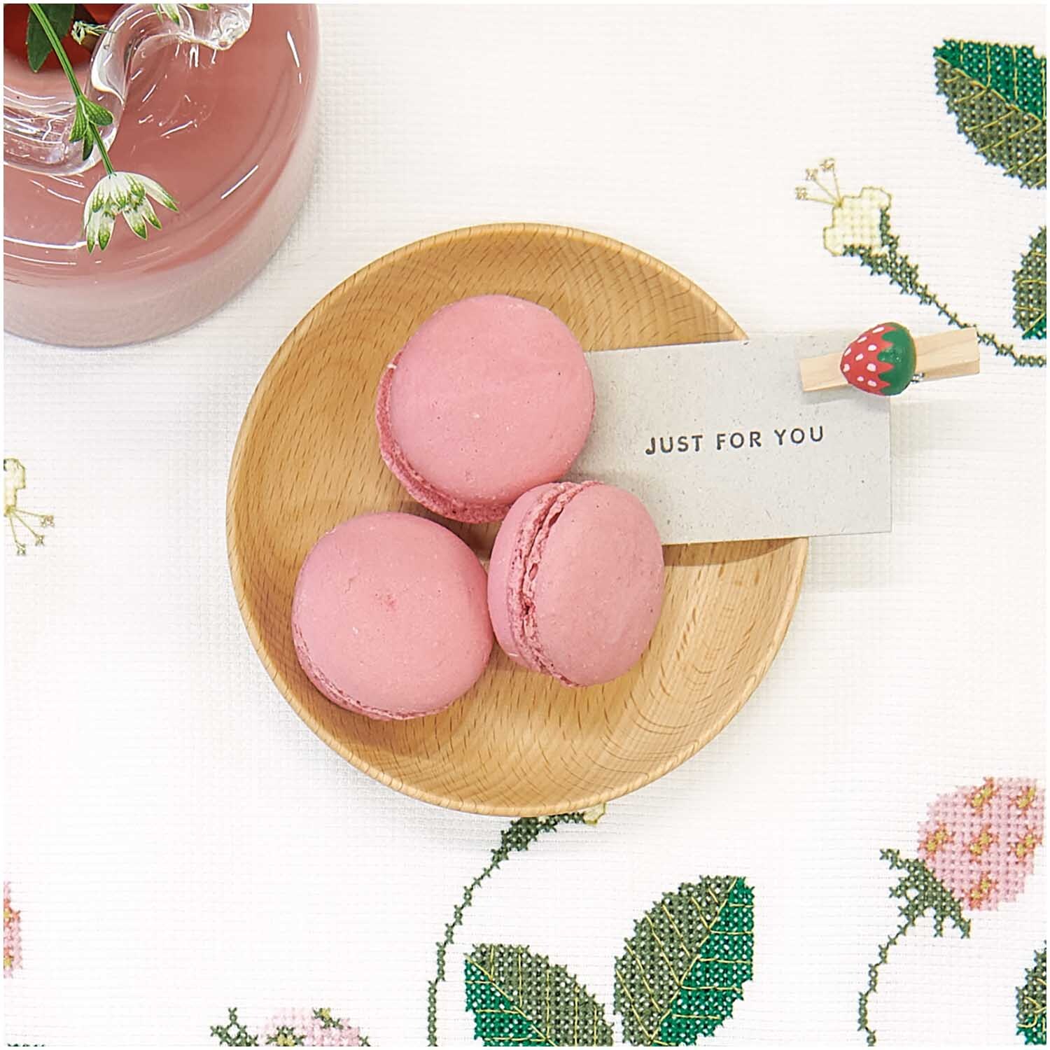 Holzklammern Erdbeere 8 Stück von Rico Design Holzklammern Erdbeere 8 Stück von Rico Design: Rosa Macarons auf Holzplatte mit Erdbeerklammer und Grußkarte auf bestickter Tischdecke.