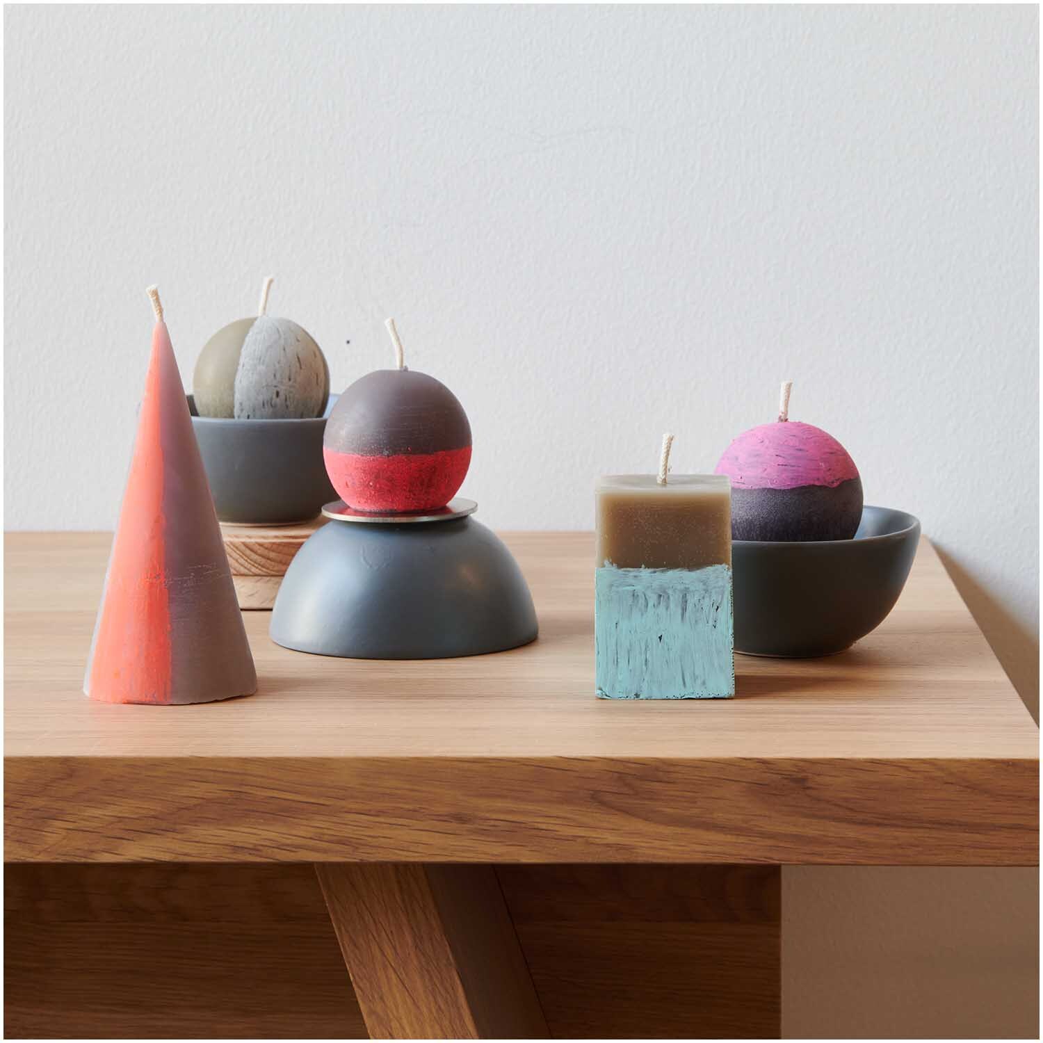 Kerzengießform Kugel 74x74x65mm von Rico Design Kerzengießform Kugel 74x74x65mm: Verschiedene bunte Kerzenformen auf einem Holztisch arrangiert.