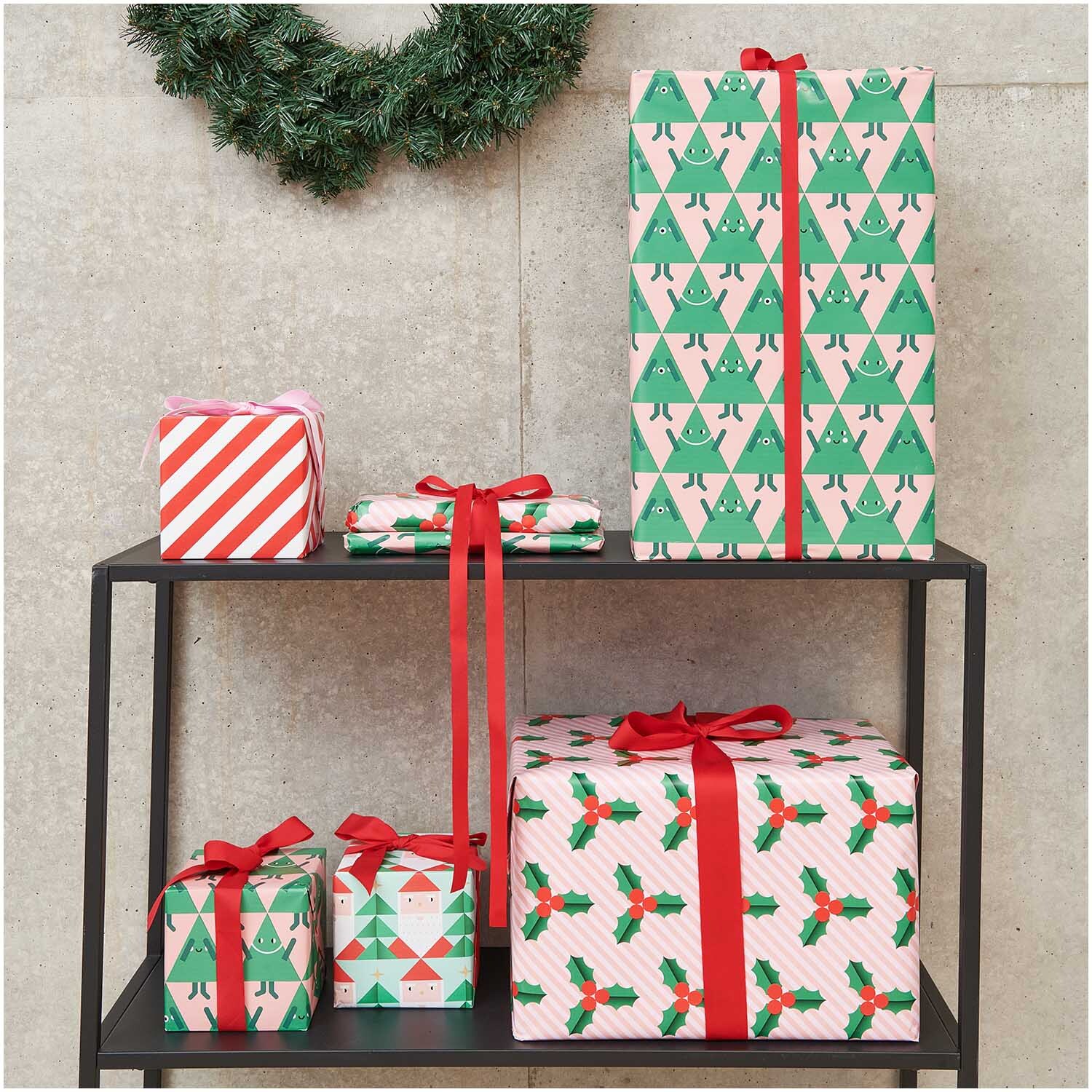 Paper Poetry Geschenkpapier Weihnachtsmann & Tannen 70cm 2m 80g/m² von Rico Design Paper Poetry Geschenkpapier mit Weihnachtsmann- und Tannenbaum-Muster, dekoriert auf einem Regal. Ideal für festliche Anlässe.