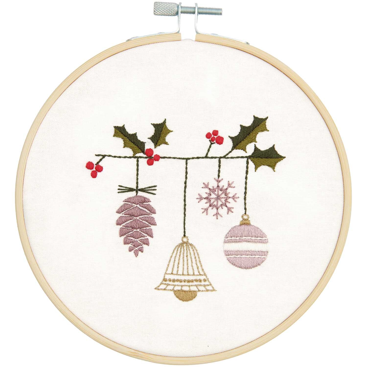 Stickpackung Grafische Glocke Bild Ø 15cm zeigt weihnachtliche Motive mit Tannenzapfen, Glocke und Kugel, verziert mit Stechpalmenzweigen und Beeren.