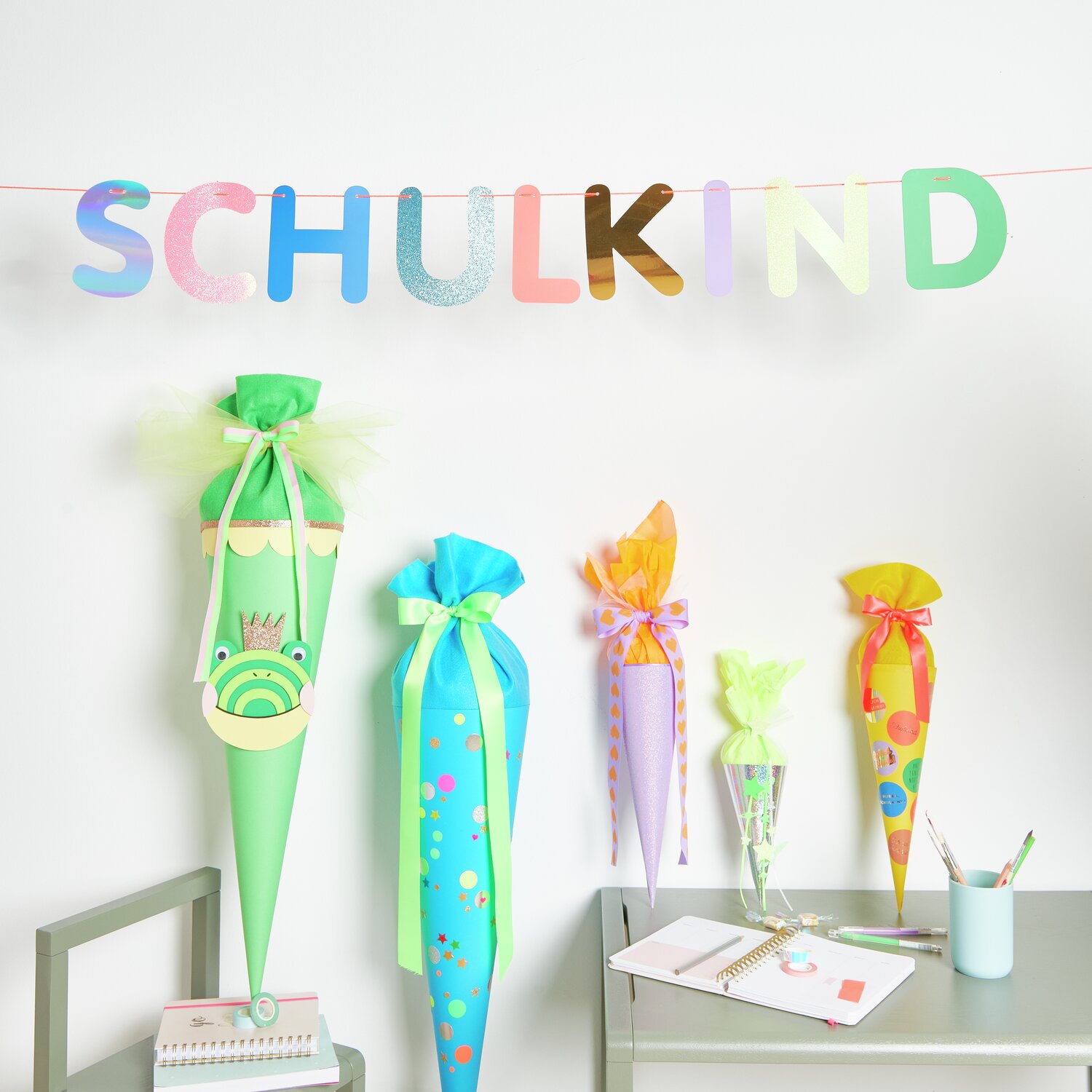 Paper Poetry Girlande Schulkind: Bunte Schultüten mit Filz- und Tüllverschlüssen, dekoriert in verschiedenen Farben.
