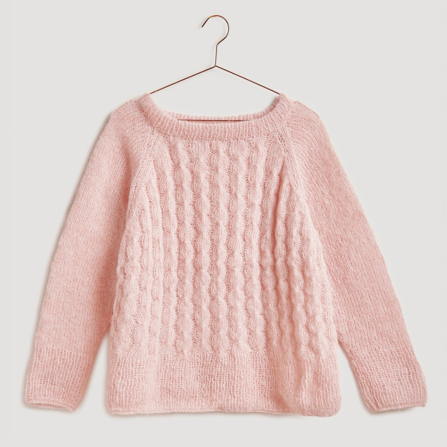 Strickset Pullover Modell 07 aus Die Neue Masche No. 13, apricot, mit Zopfmuster, auf einem Bügel. Ideal für Herbstmode.