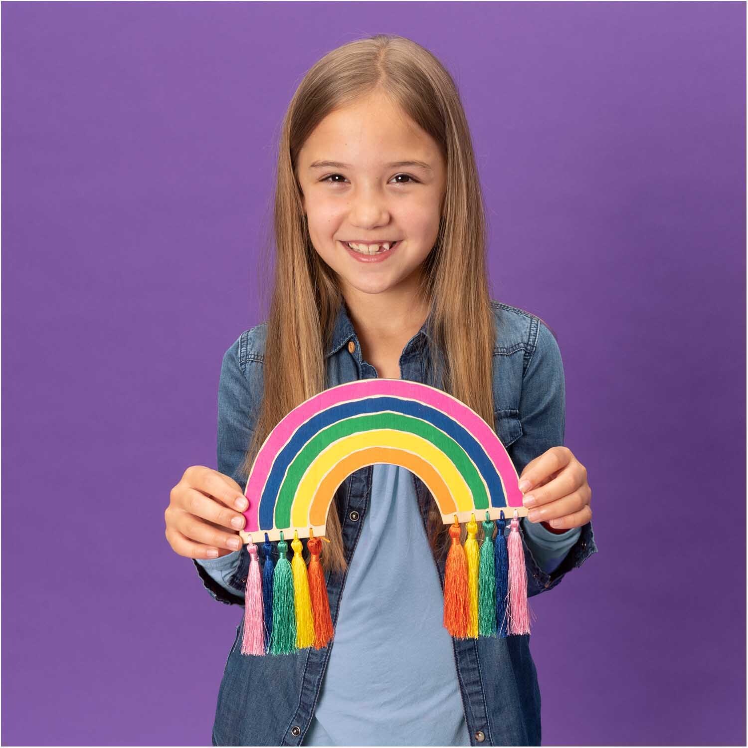 Quasten fein 9cm 5 Stück Farbe Regenbogen von Rico Design Quasten fein 9cm 5 Stück: Ein Mädchen hält einen bunten Regenbogen mit Quasten von Rico Design.