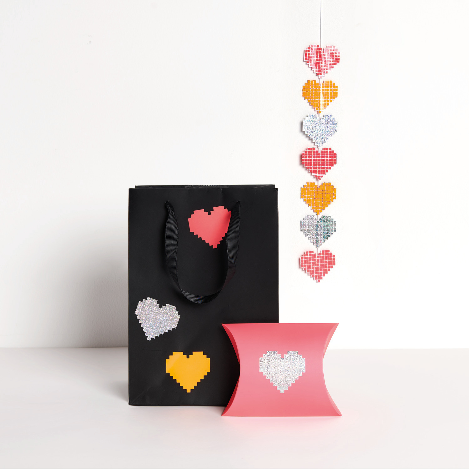Paper Poetry Sticker Herzen auf der Rolle Ø5cm 100 Stück von Rico Design Paper Poetry Sticker Herzen auf der Rolle: Schwarze Tasche und rosa Box mit Herzmotiven, dekorativ arrangiert.